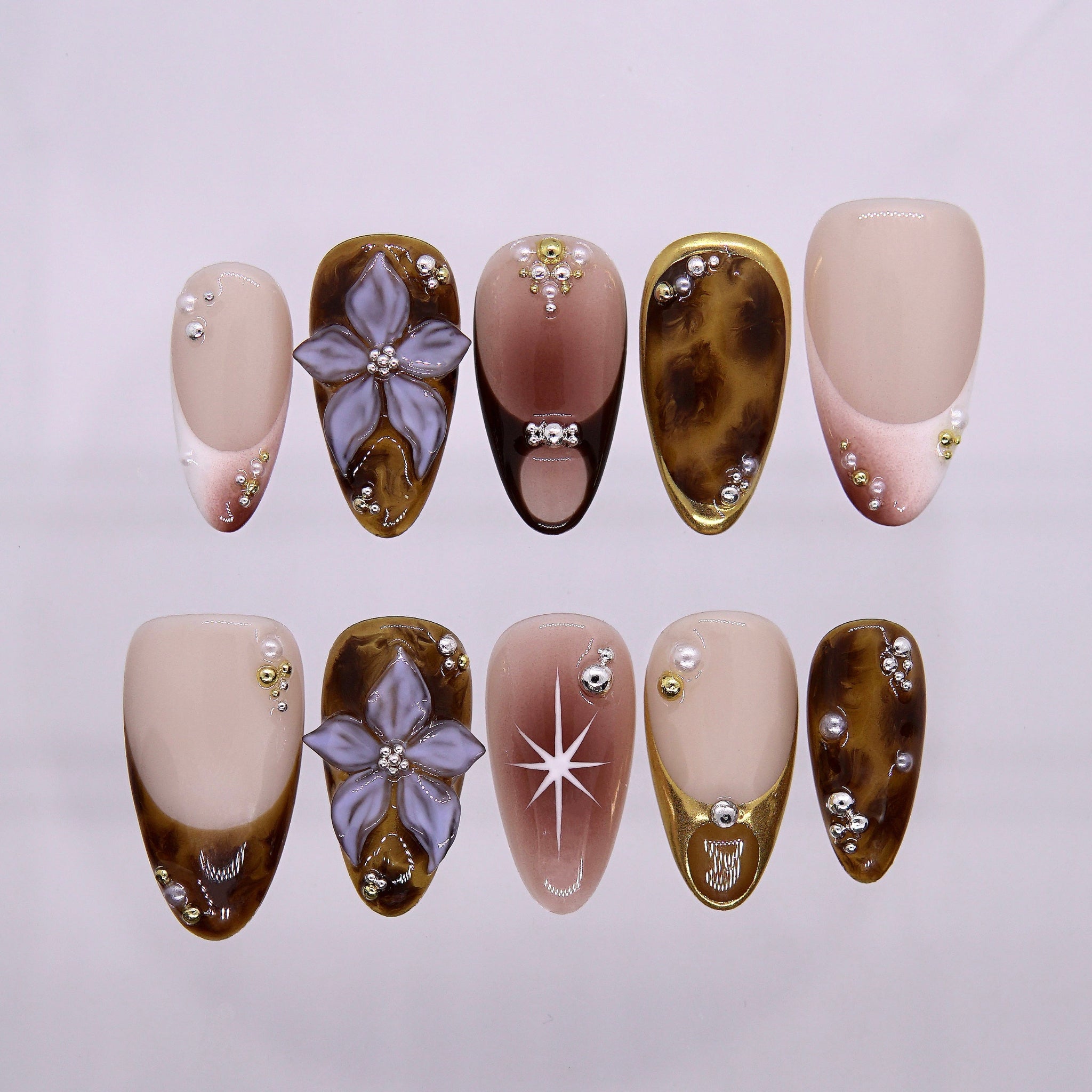 Amber tortoiseshell press-on nails with nude tones and starburst accents.