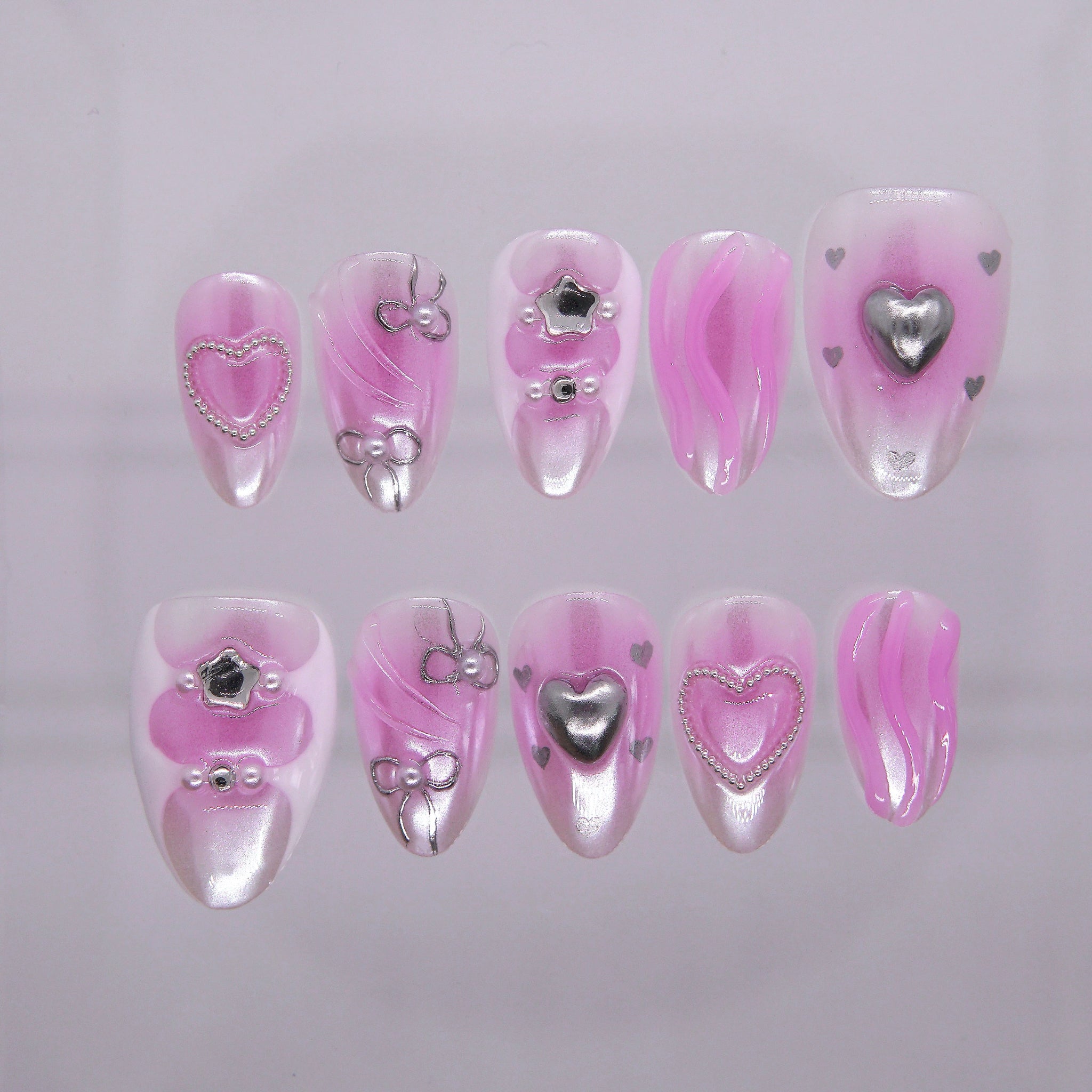 Glossy bubblegum pink press-on nails with silver heart details and chrome accents – full set view