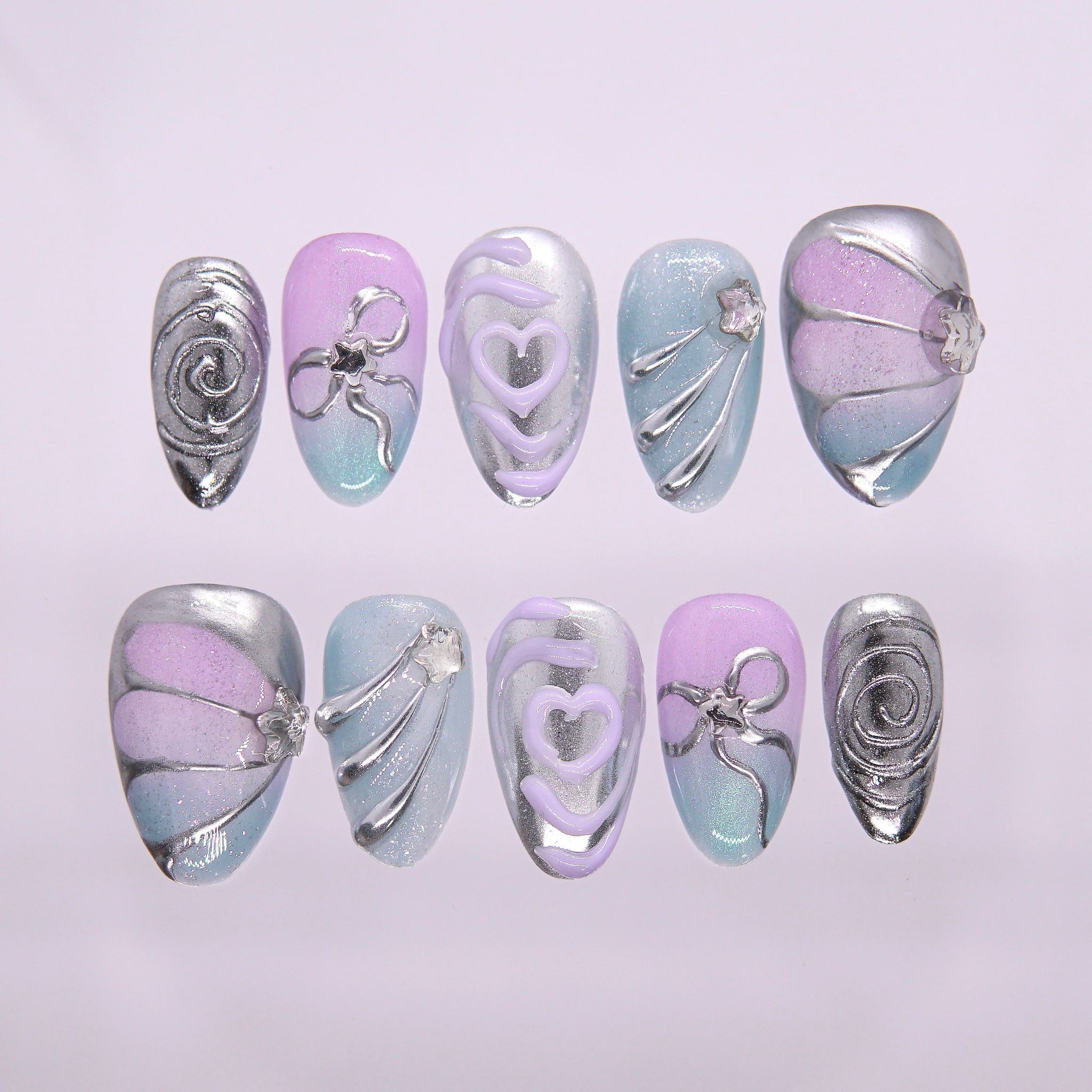 Flat lay of a pastel chrome nail set featuring sculptural silver lines and gradient tones.