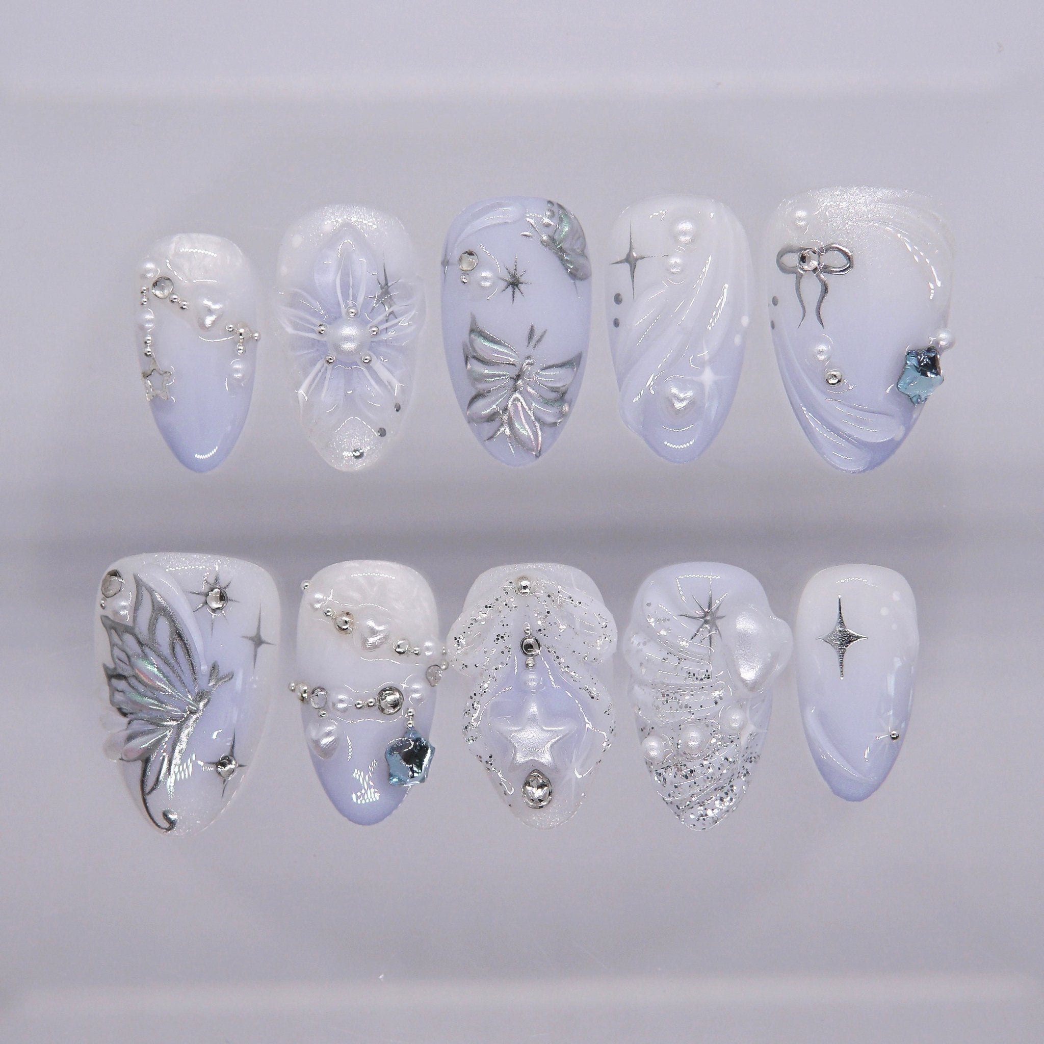 Moonlit Wings press-on nails with icy blue and pearly white gradient, silver butterflies, and star accents – dreamy Water · Flow design by Nailsium.