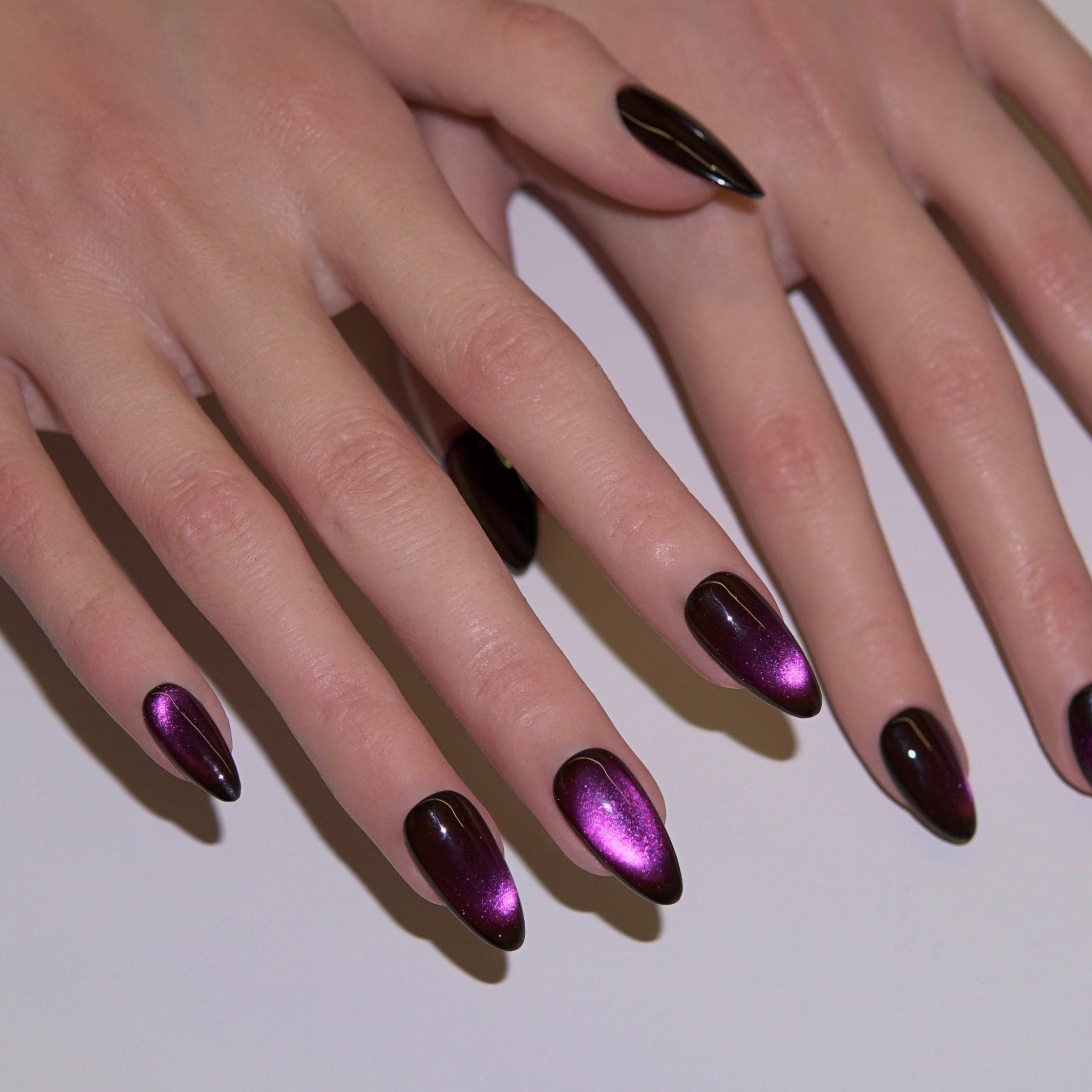 Close-up of purple cat-eye press-on nails reflecting violet light, symbolizing clarity, intuition, and mystical elegance.