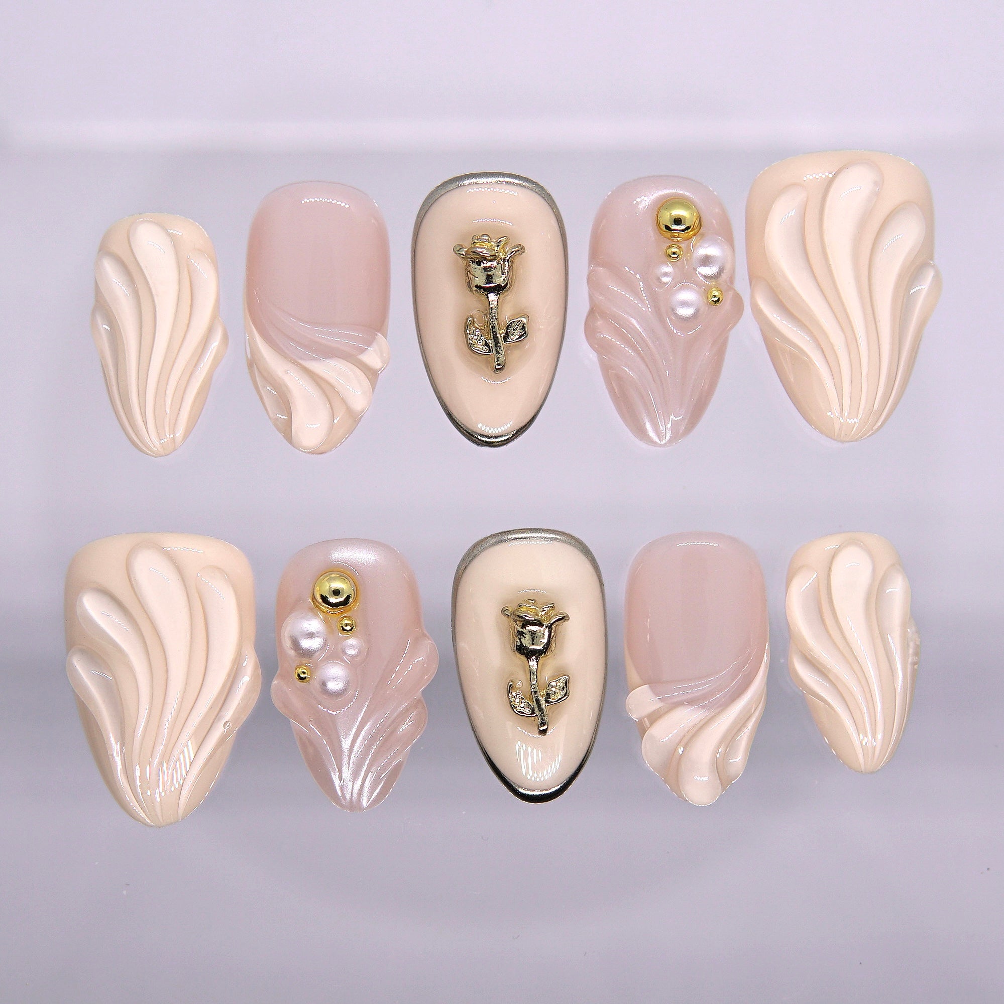 Rosewater Shell nude press-on nails with 3D sculpted shell texture, pearl accents, and gold rose charm from Nailsium Earth · Calm series.