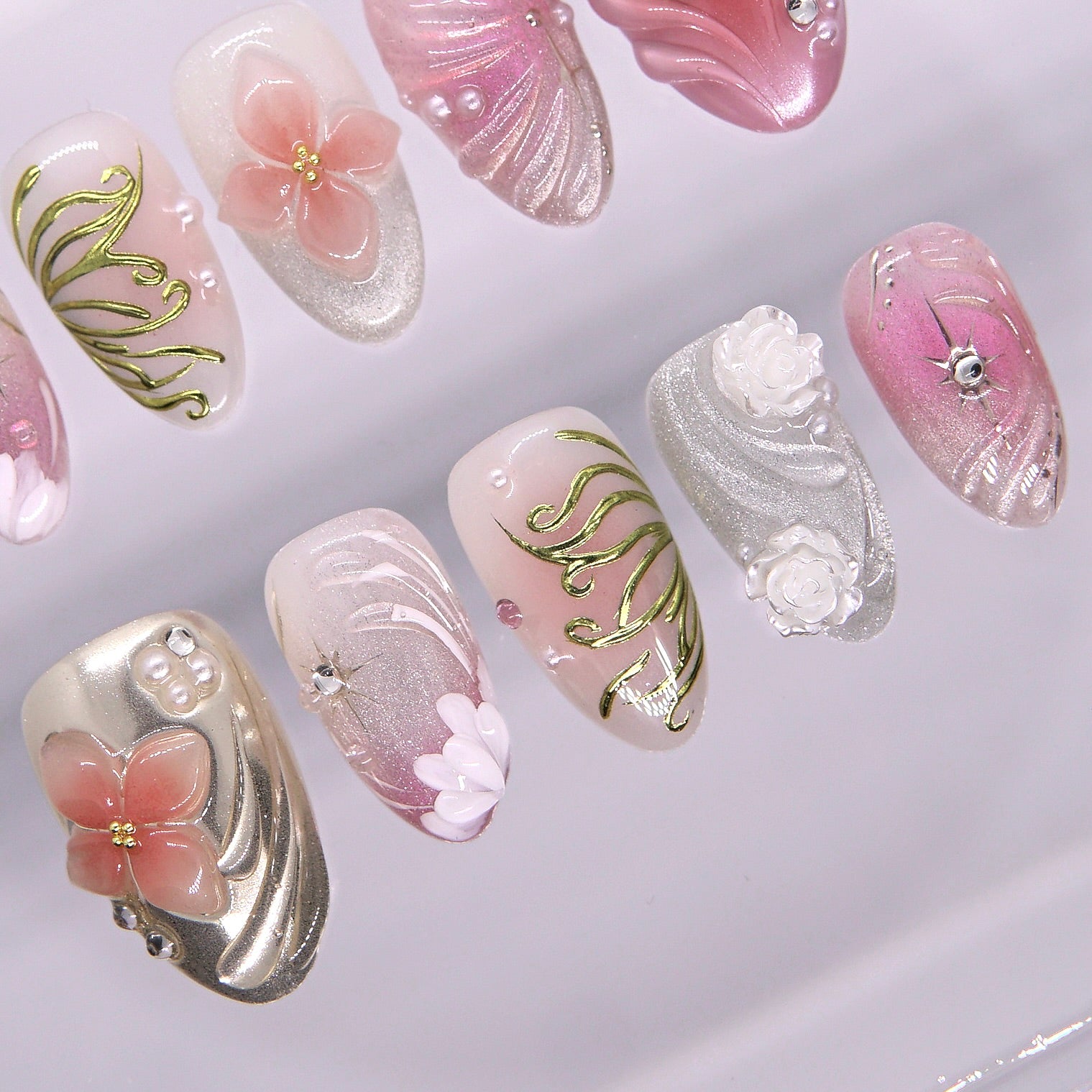 Golden vine carvings on champagne shimmer press-on nail with pearl details.