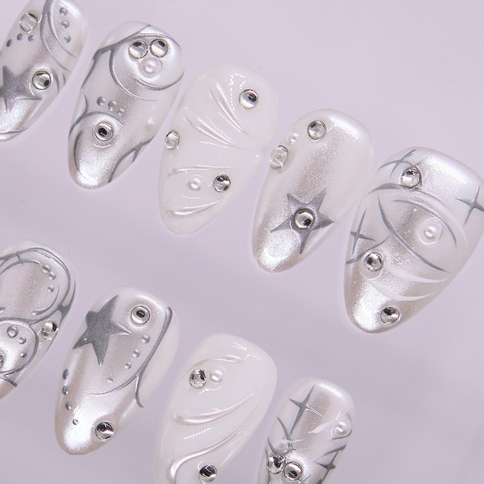 Glossy chrome silver and pearly white press-on nails with futuristic star details.