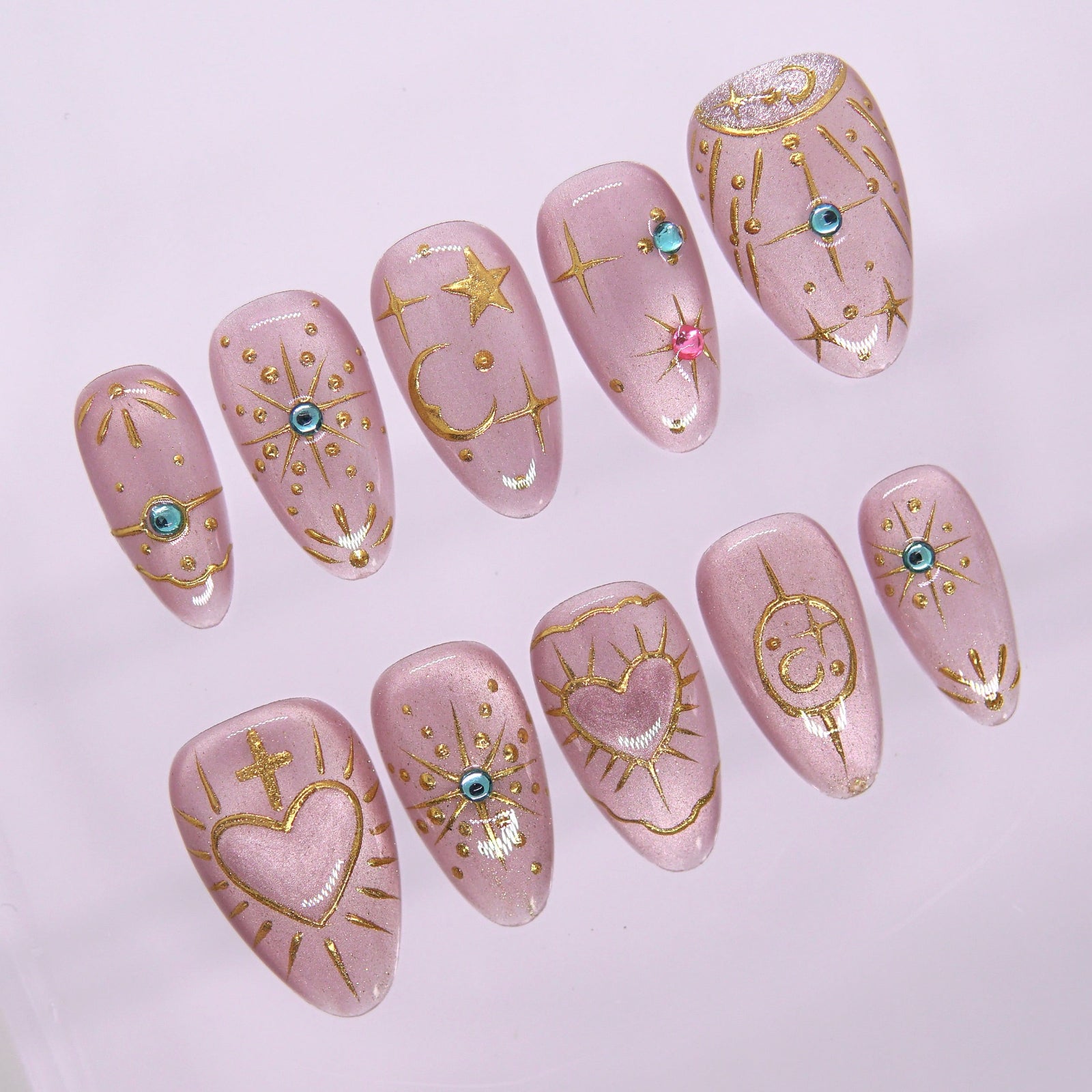 Close-up of hand-painted gold stars, hearts, and symbols on soft lilac press-on nails.