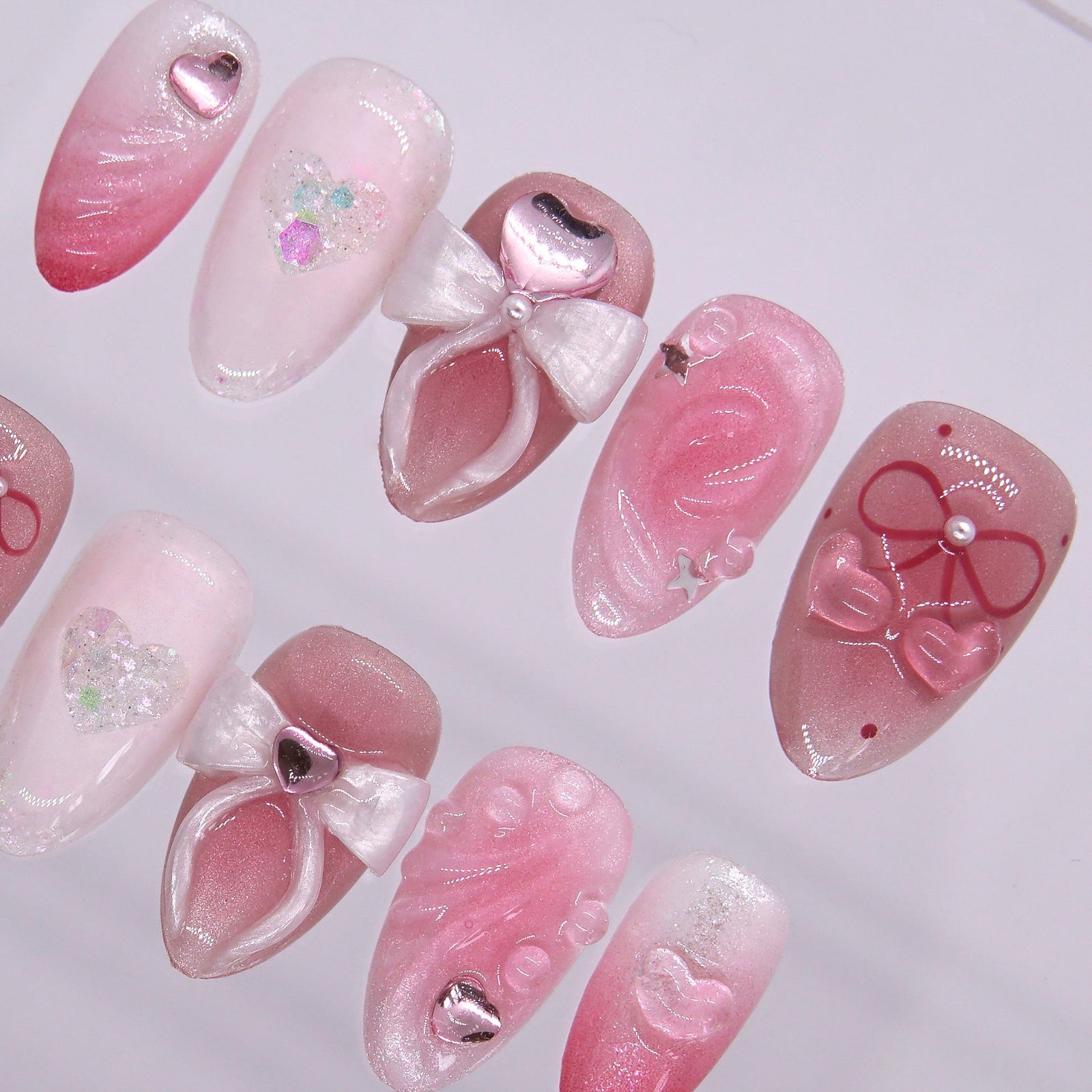 Close-up of 3D white bow on a blush pink nail, with heart gem accent and pearly finish.