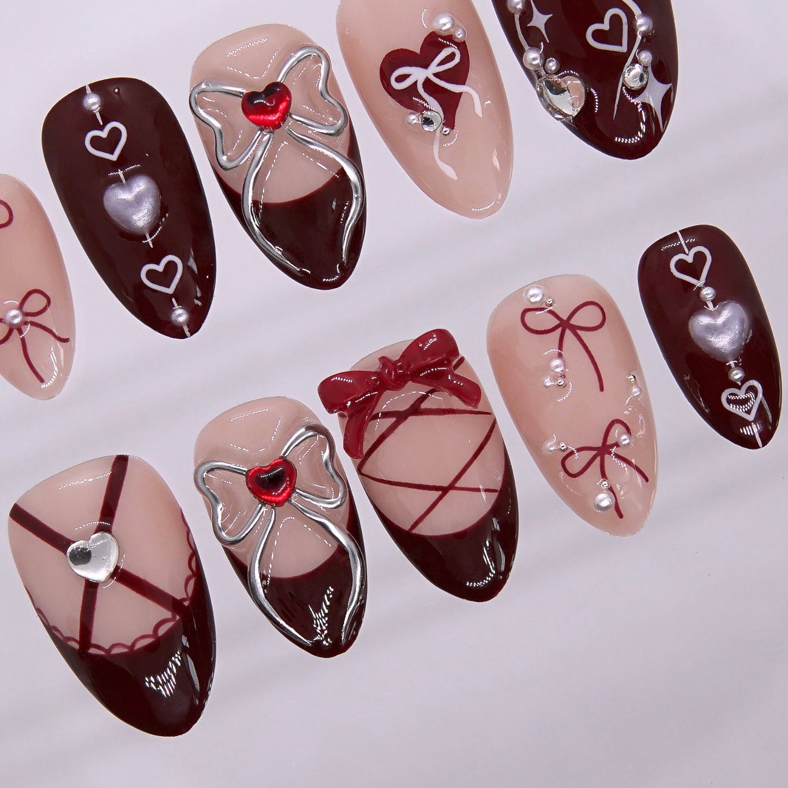Close-up of lace-up nail design with silver bows and heart charms.