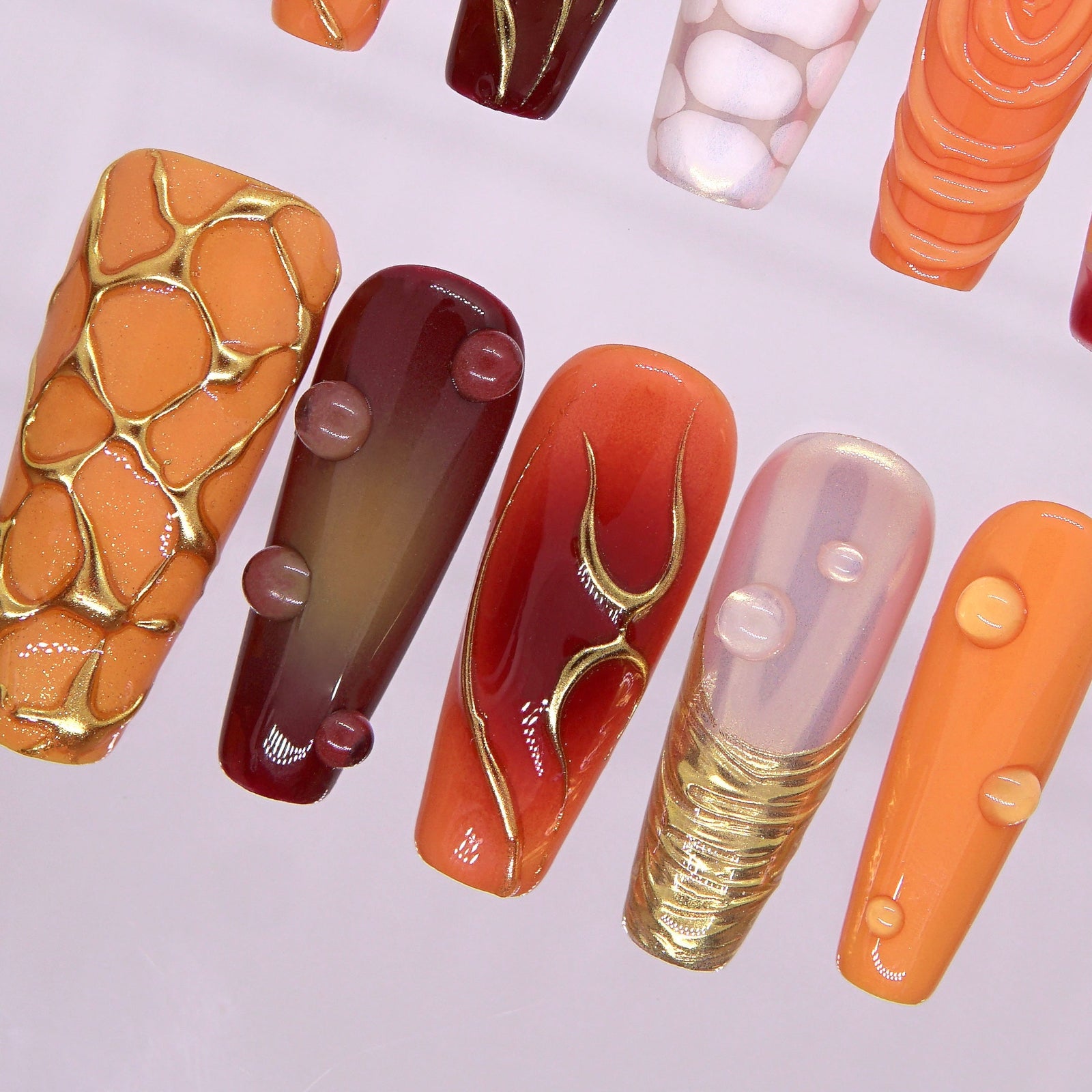 Close-up of lava-textured gold line accents on Torrey Burn nails with red gradient base and reflective top coat.