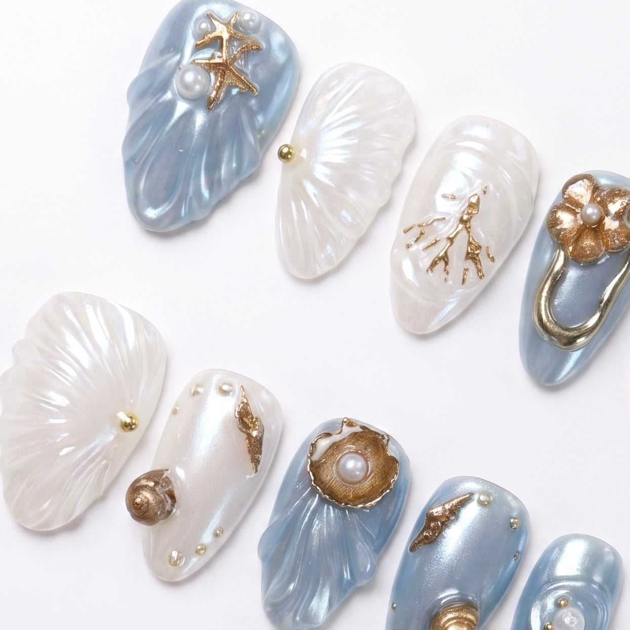 Blue and white sculpted nails with coral branches, shell ridges, and metallic gold details.