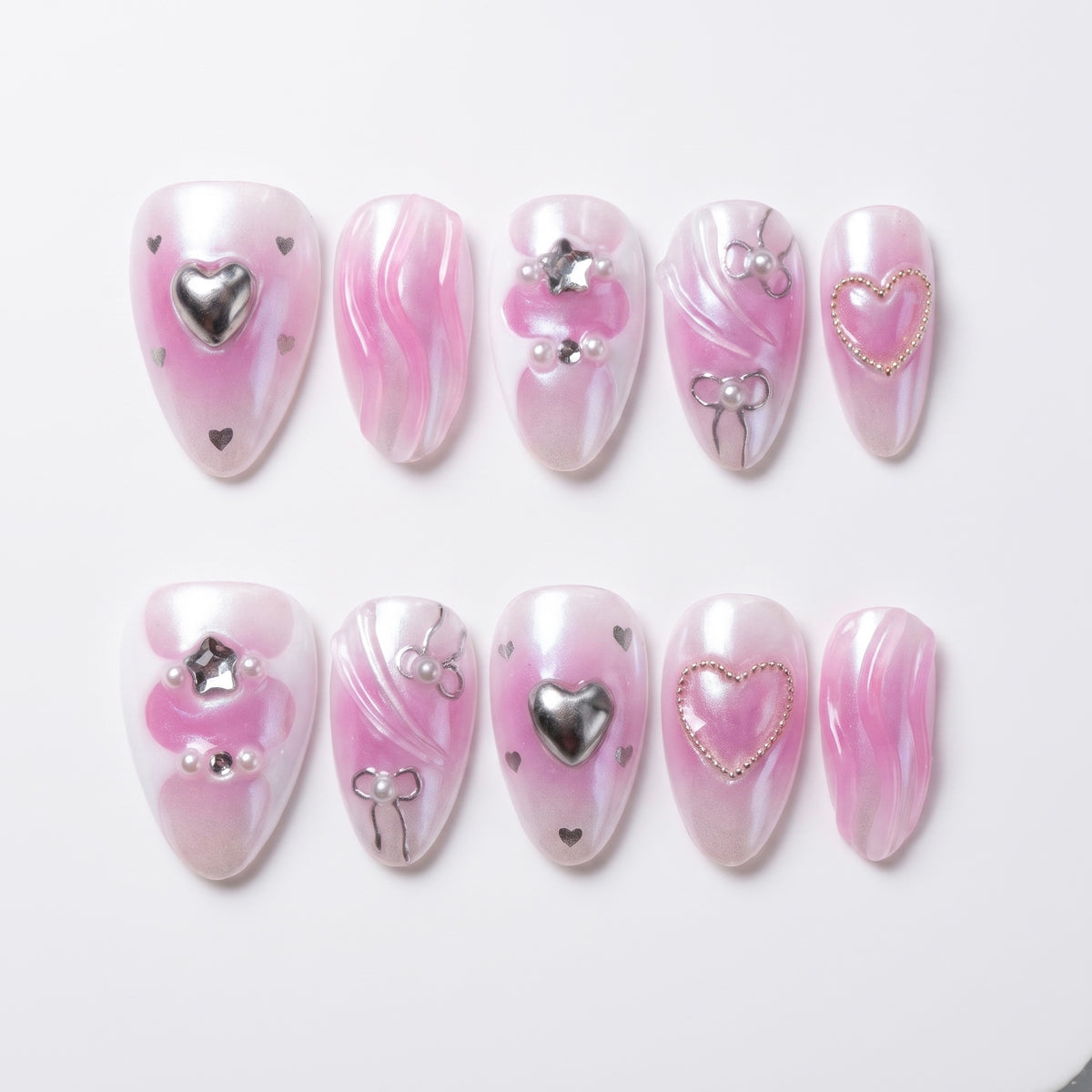 Glossy bubblegum pink press-on nails with silver heart details and chrome accents – full set view