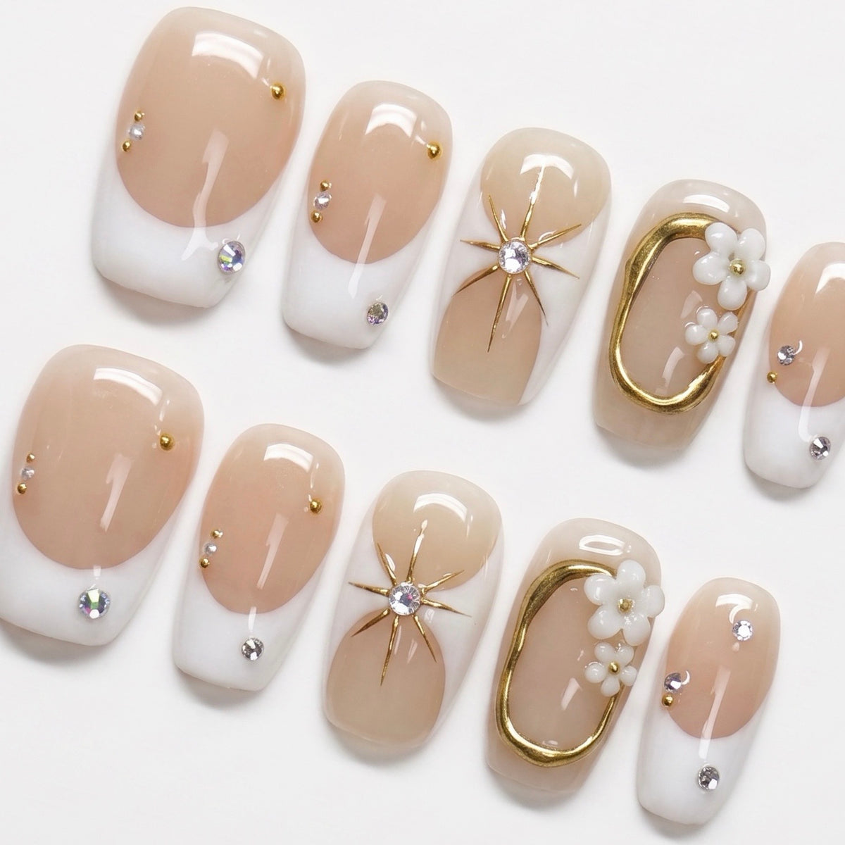 Close-up of soft nude nails with white tips and small crystal details