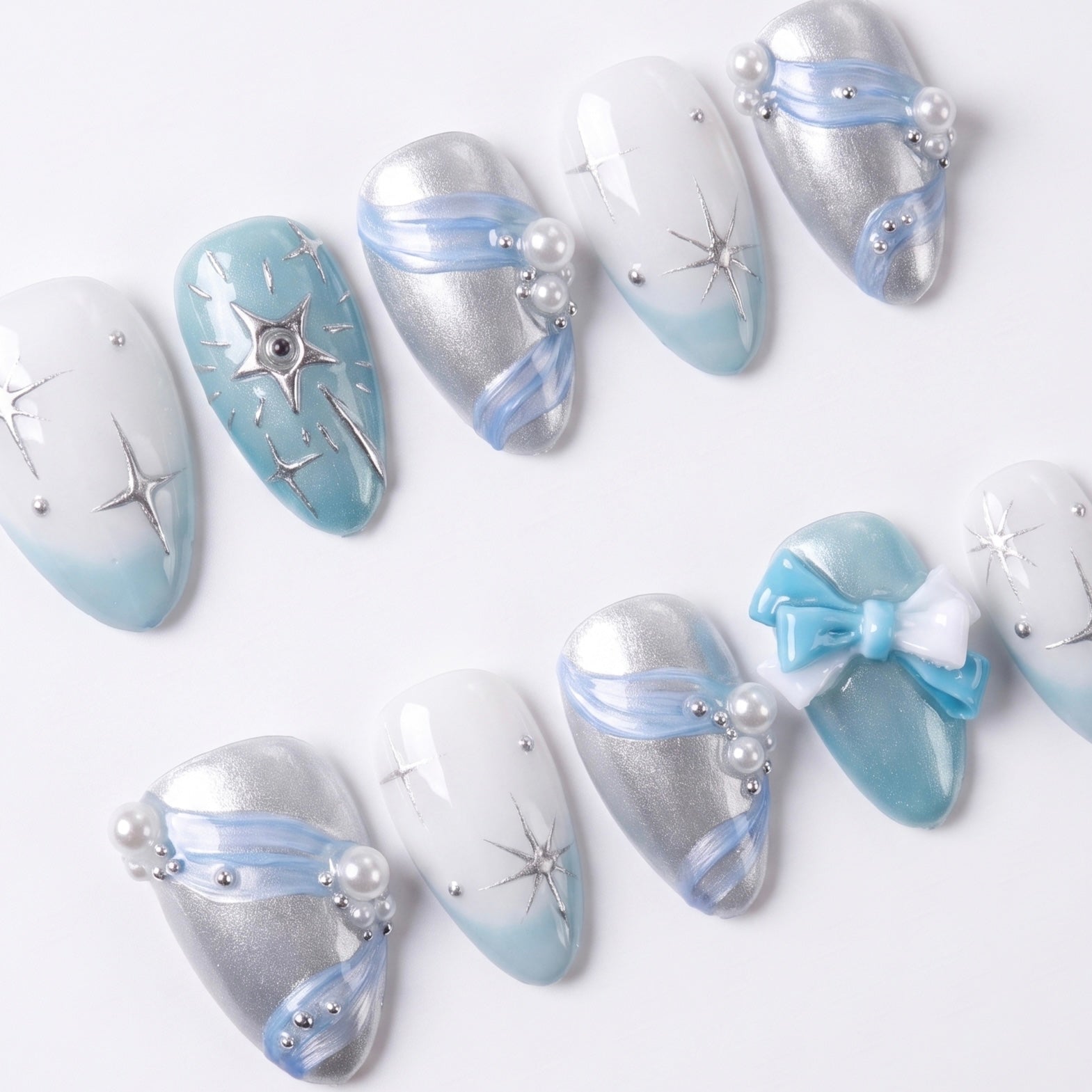 Close-up of blue nails with soft shimmer, pearl accents, and delicate bow charm