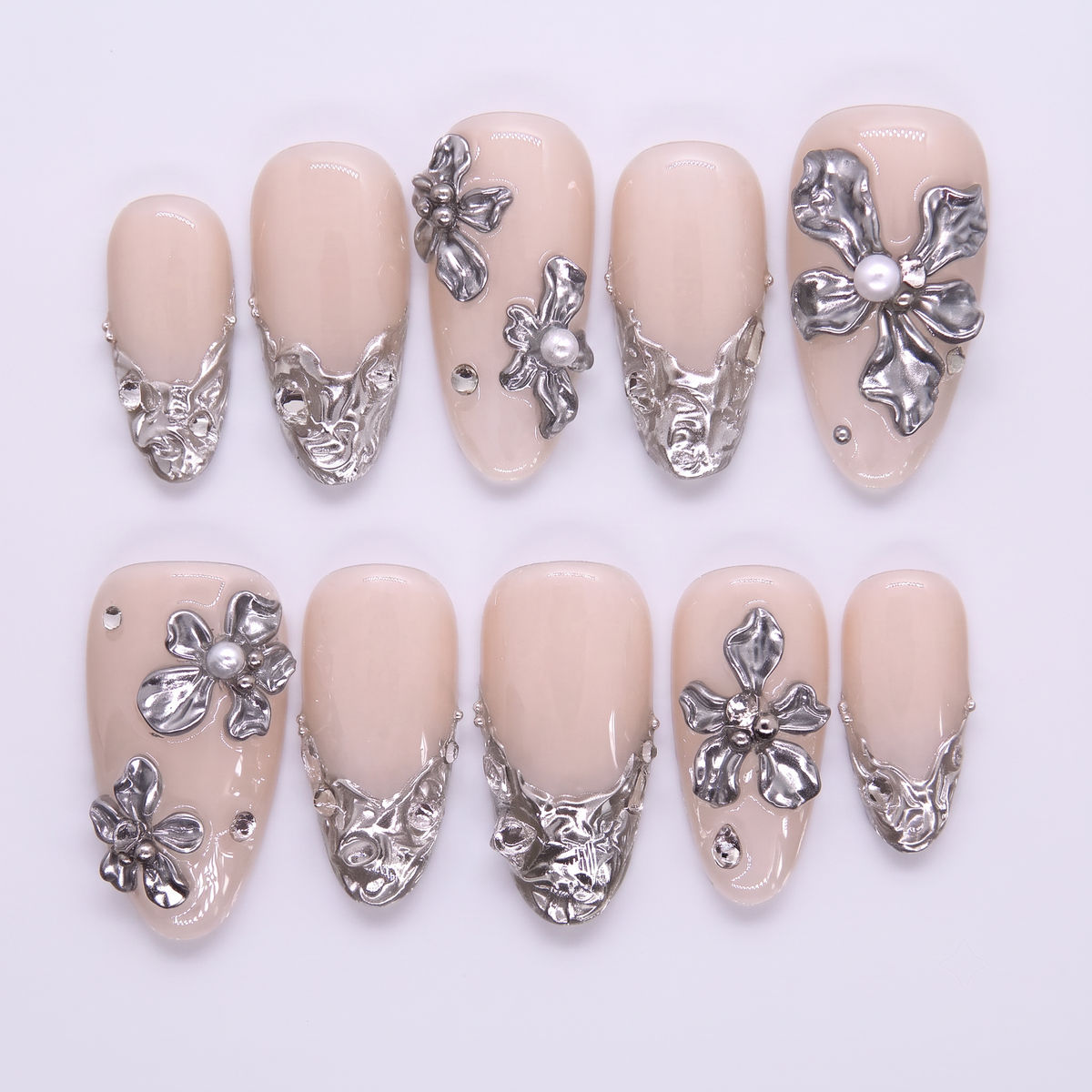 Cuvier Cliffs press-on nails laid out flat on white background, featuring creamy nude base and sculpted silver floral overlays—designed to echo La Jolla’s iconic cliffside wedding site.