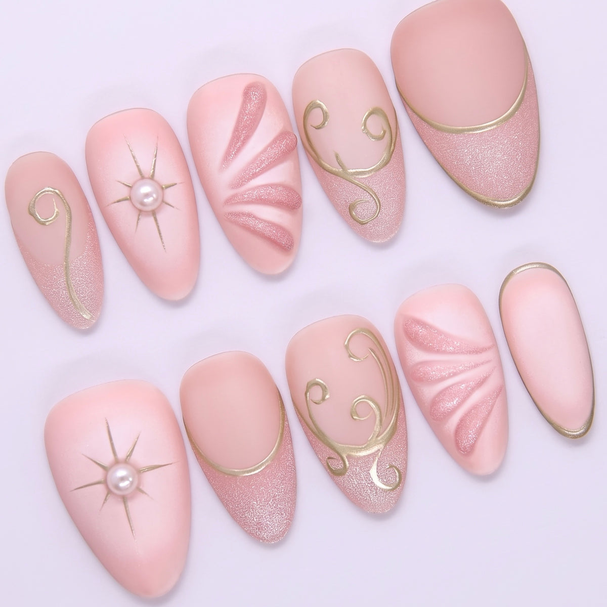 Close-up of Begin with Trust press-on nails showing gold celestial symbols and delicate blush pink base