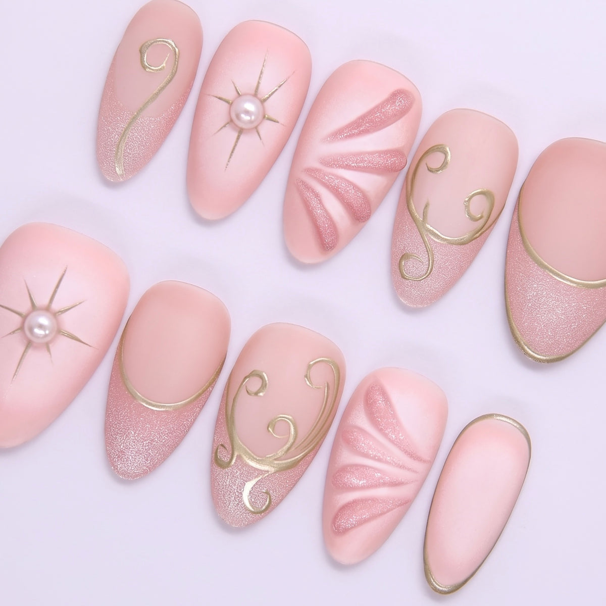 Close-up of Begin with Trust press-on nails showing gold celestial symbols and delicate blush pink base