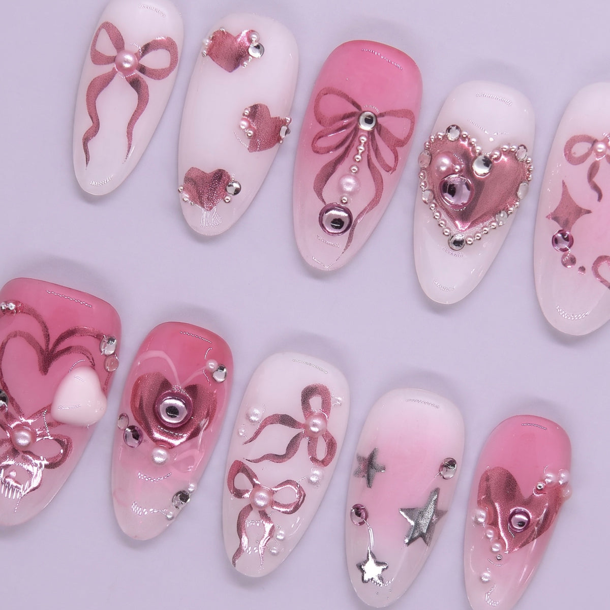 Close-up of pink and white bow nail design with rhinestone and pearl accents.
