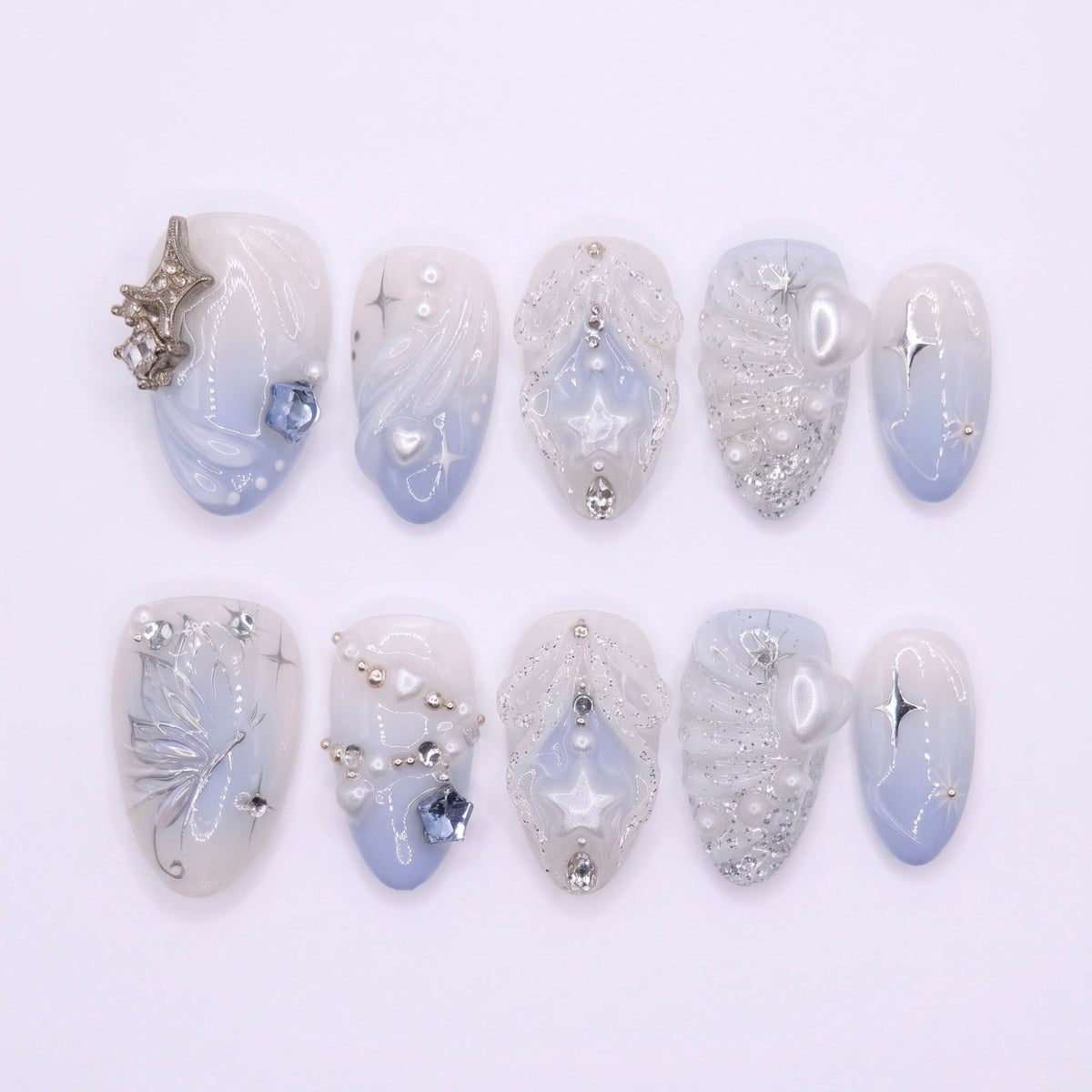 Moonlit Wings press-on nails with icy blue and pearly white gradient, silver butterflies, and star accents – dreamy Water · Flow design by Nailsium.
