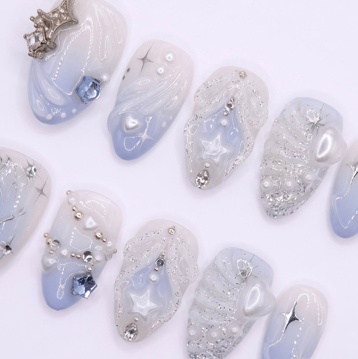 Close-up of silver butterfly wings and star trails on icy blue press-on nails.