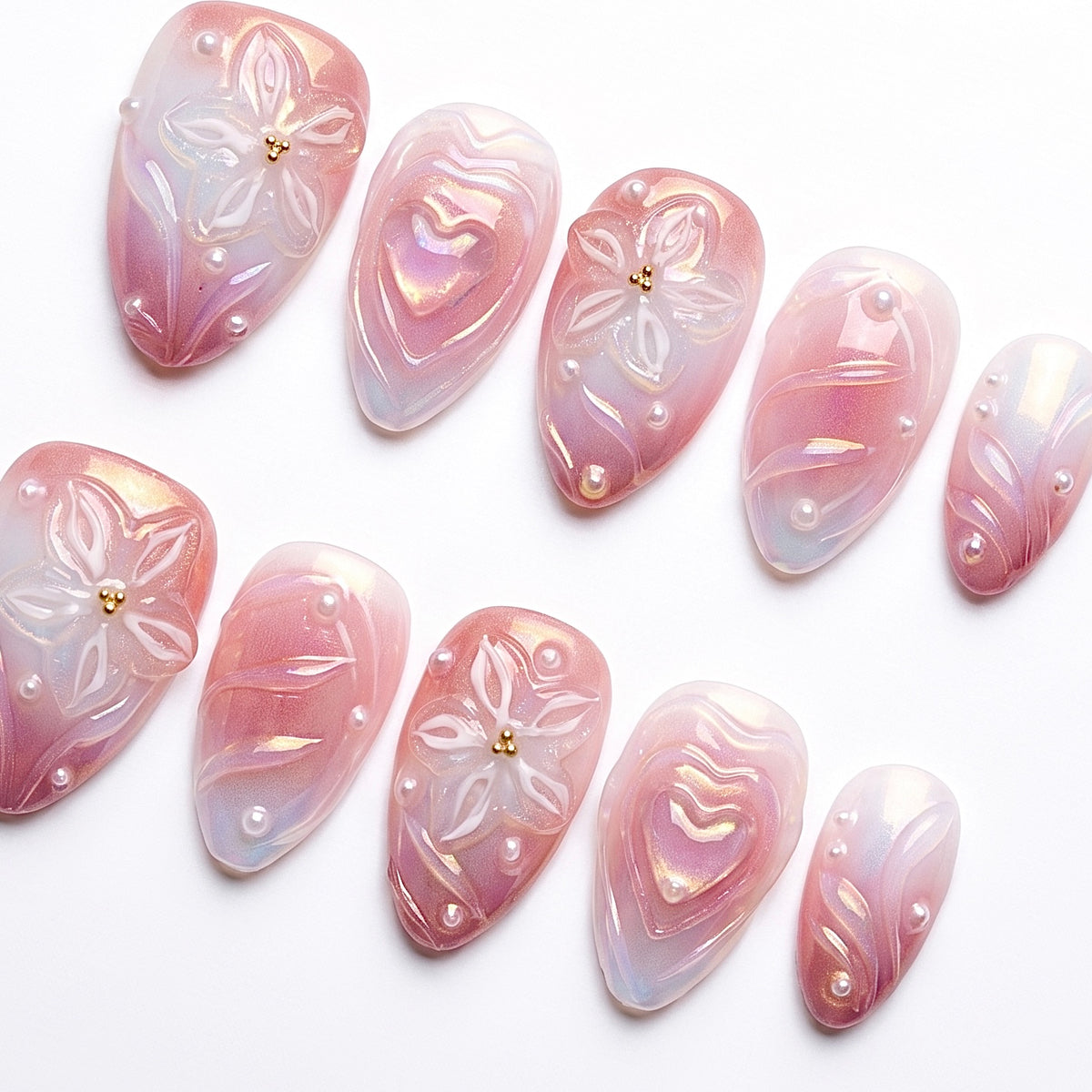 Close-up of sculpted flowers and pearls on pink gradient press-on nails.