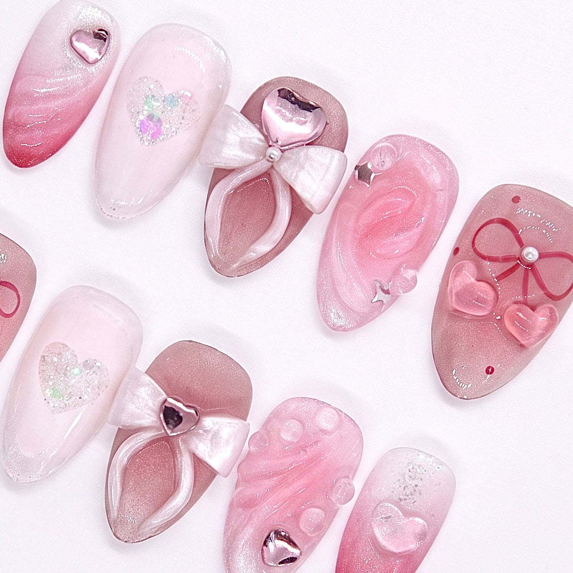 Close-up of 3D white bow on a blush pink nail, with heart gem accent and pearly finish.