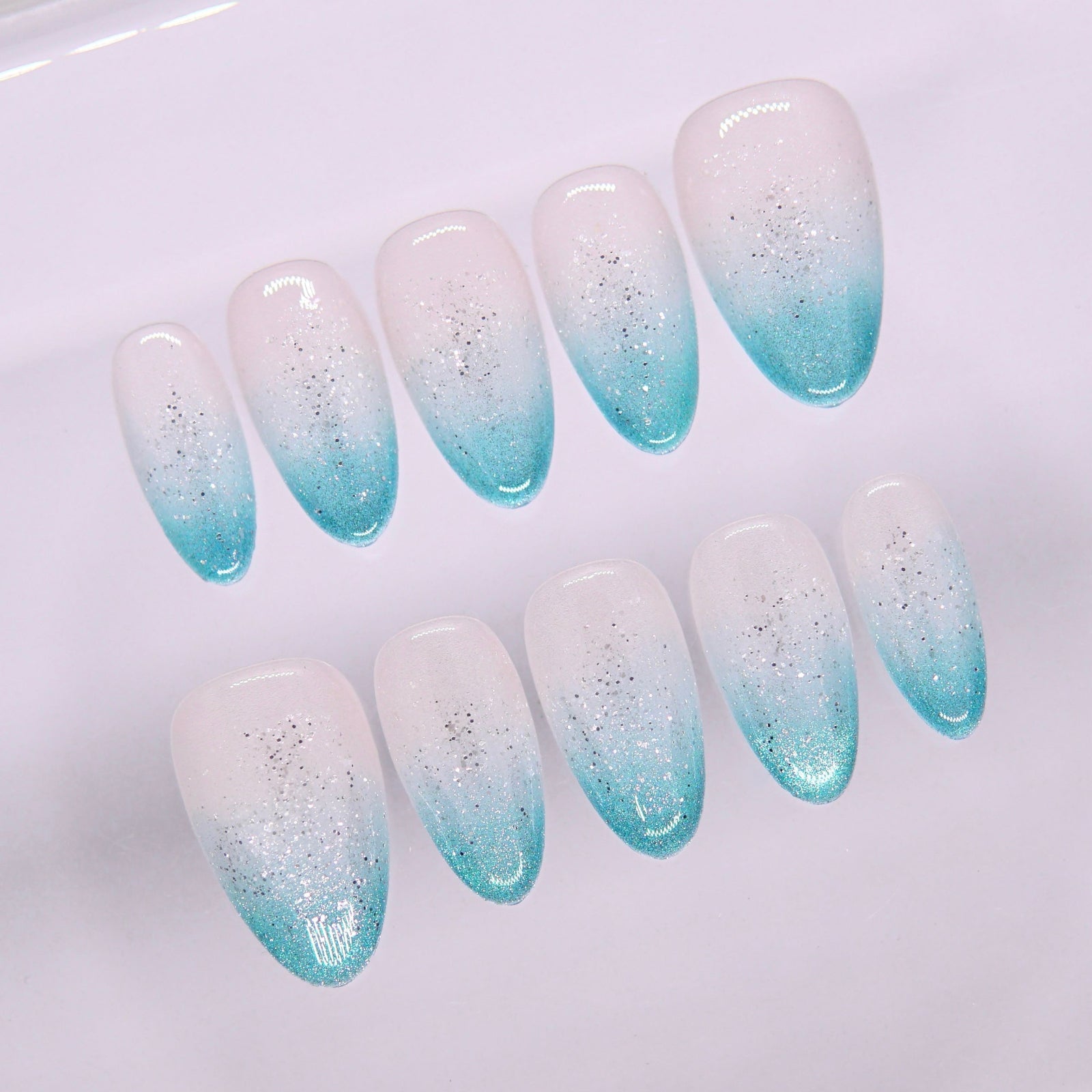 Close-up of Begin with Clarity press-on nails showing smooth blue gradient and light-reflecting shimmer

