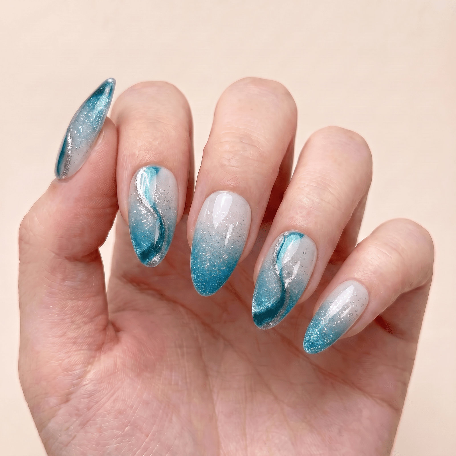 Blue shimmer press-on nails worn on hands by Nailsium