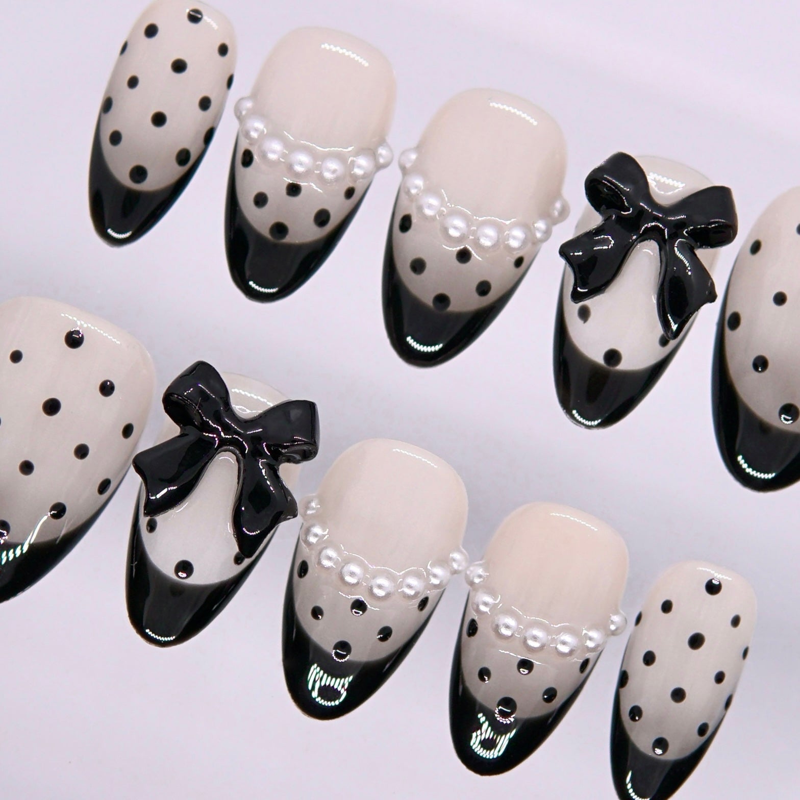 Detail view of Begin with Intention press-on nails highlighting contrast black tips, ivory base, and refined decorative elements
