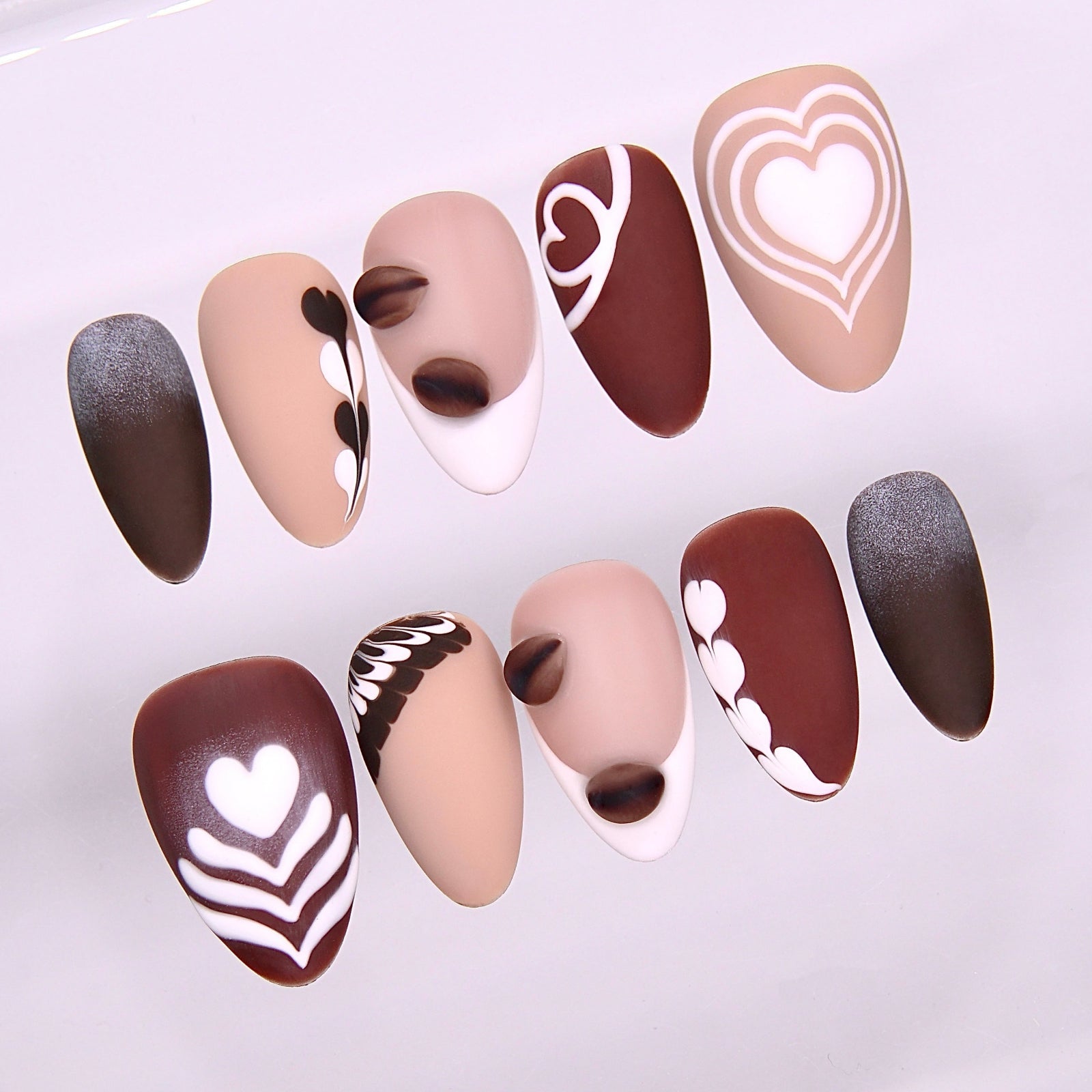 Close-up of Begin with Care press-on nails showing latte art patterns inspired by coffee foam designs