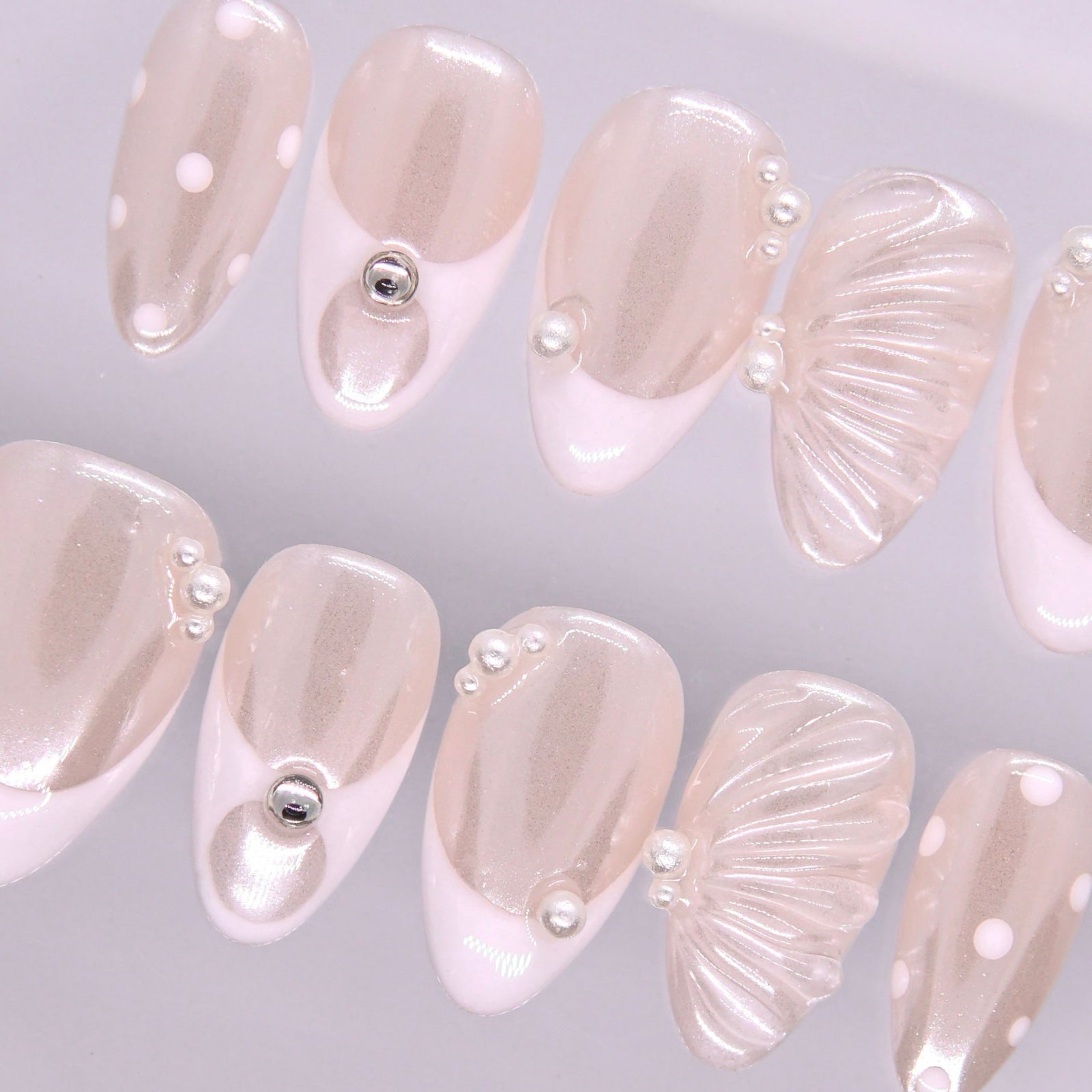 Detail view of Begin with Grace press-on nails highlighting sheer nude base and refined minimalist pearl details
