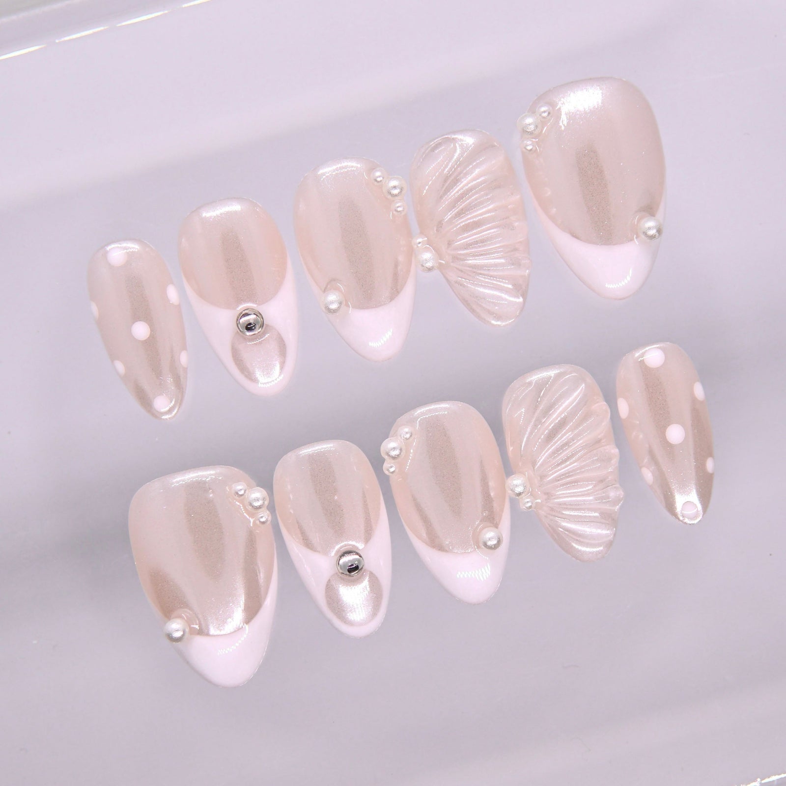 Close-up of Begin with Grace press-on nails showing pearl embellishments and soft sculptural shell-inspired texture
