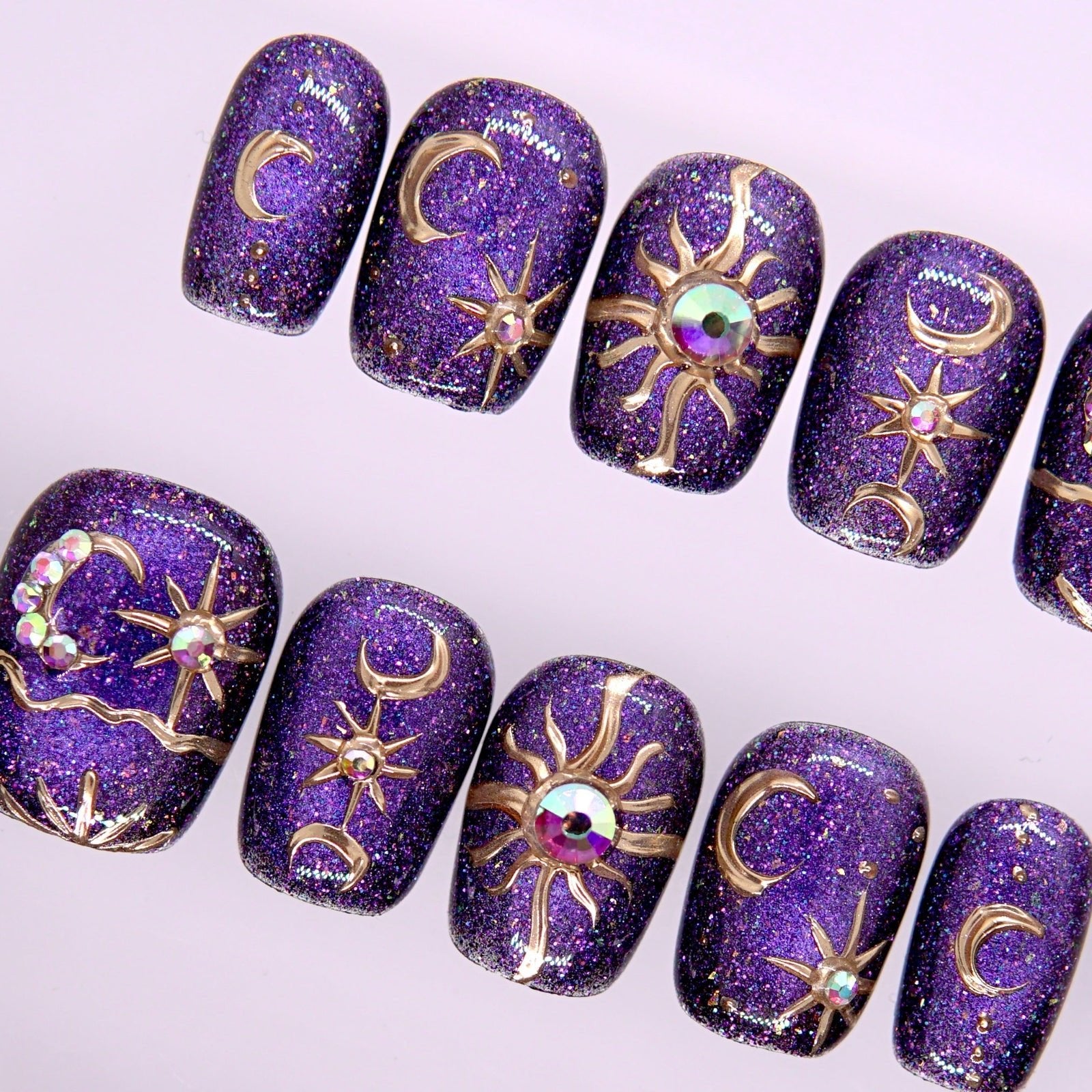 Detail view of Begin with Wonder press-on nails highlighting purple shimmer base and mystical celestial elements
