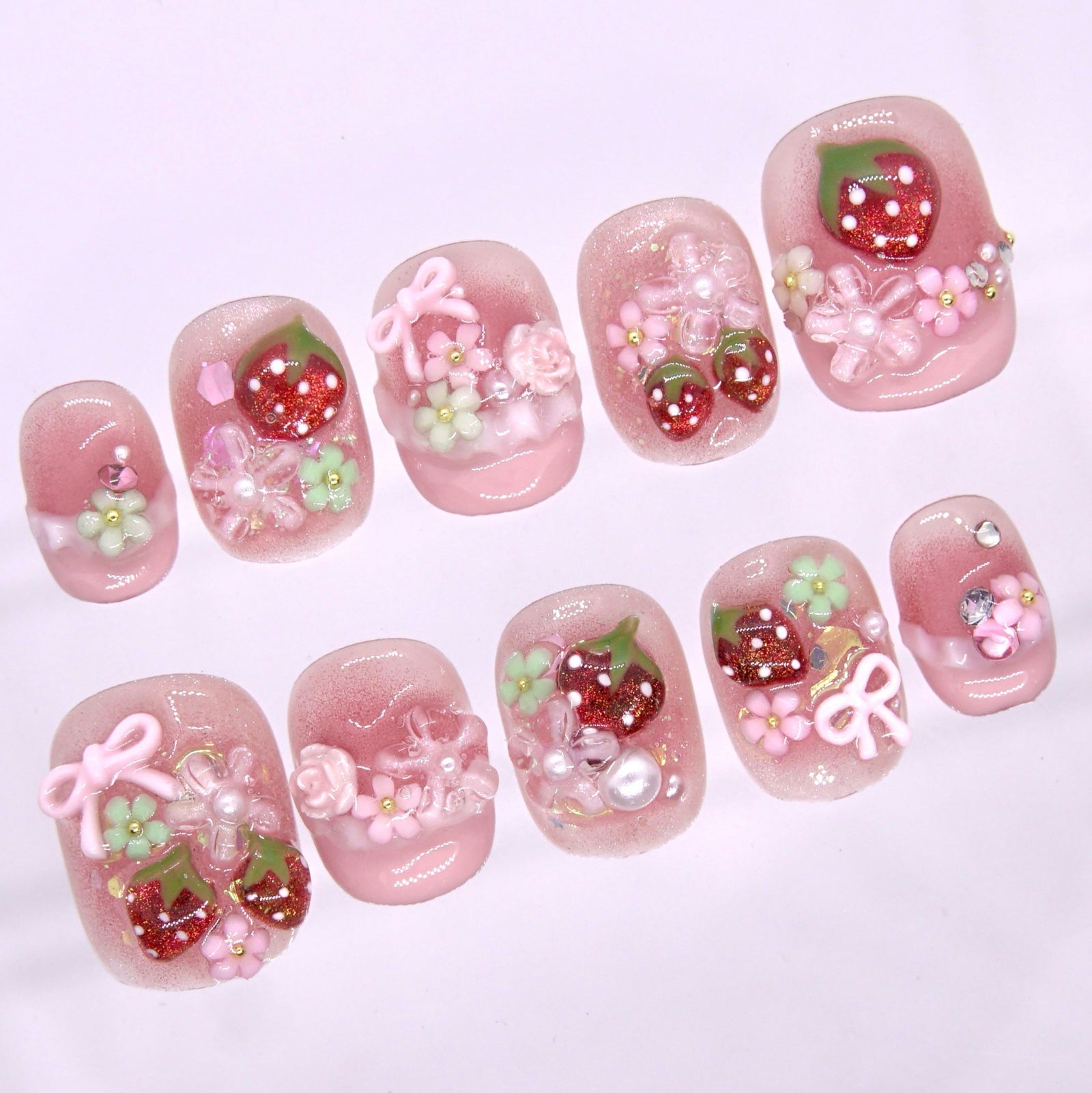 Short square pink press on nails with 3D strawberry, bow, flower, and pearl details on a glossy blush finish
