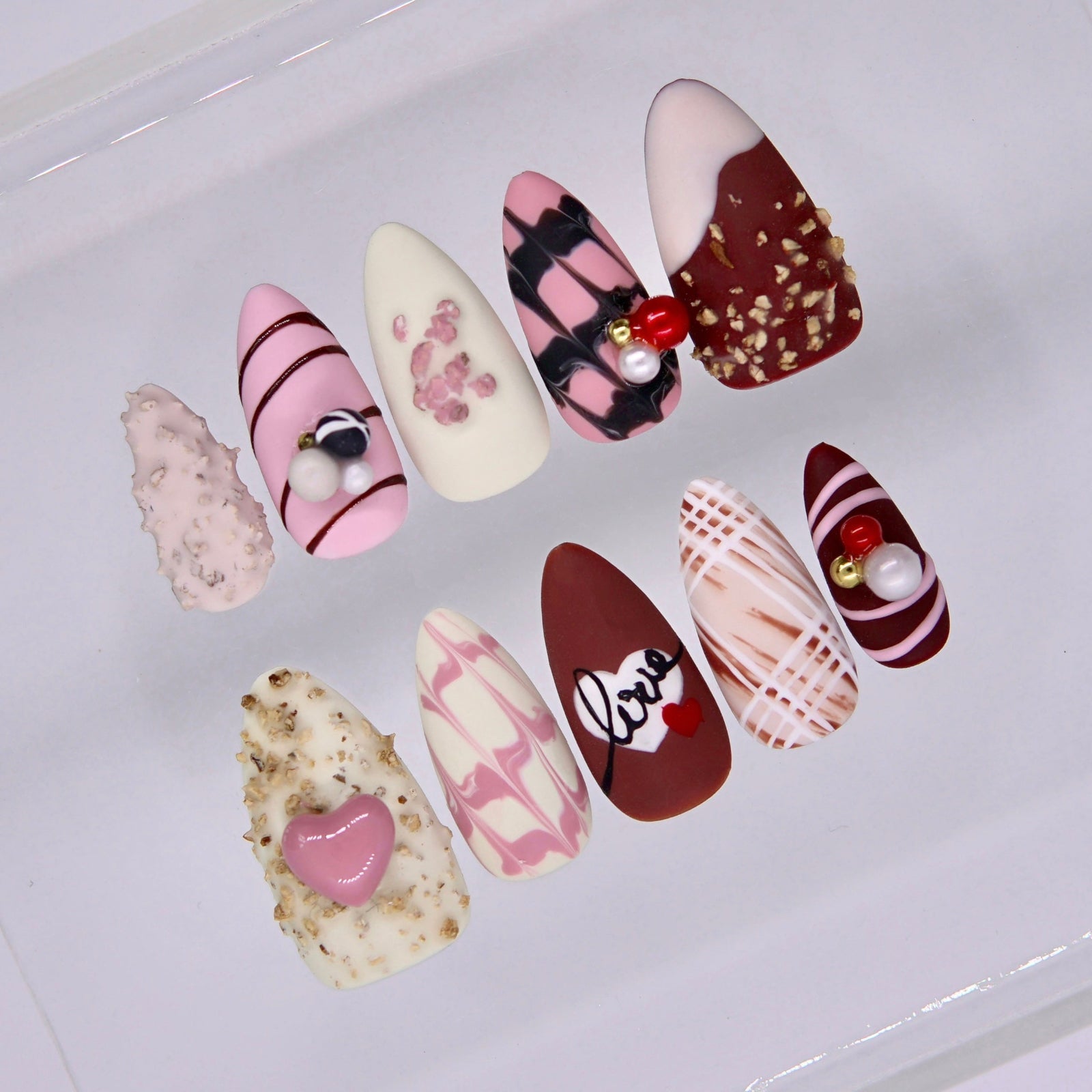 Close up of berry red press on nails with pearl embellishments and glossy finish
