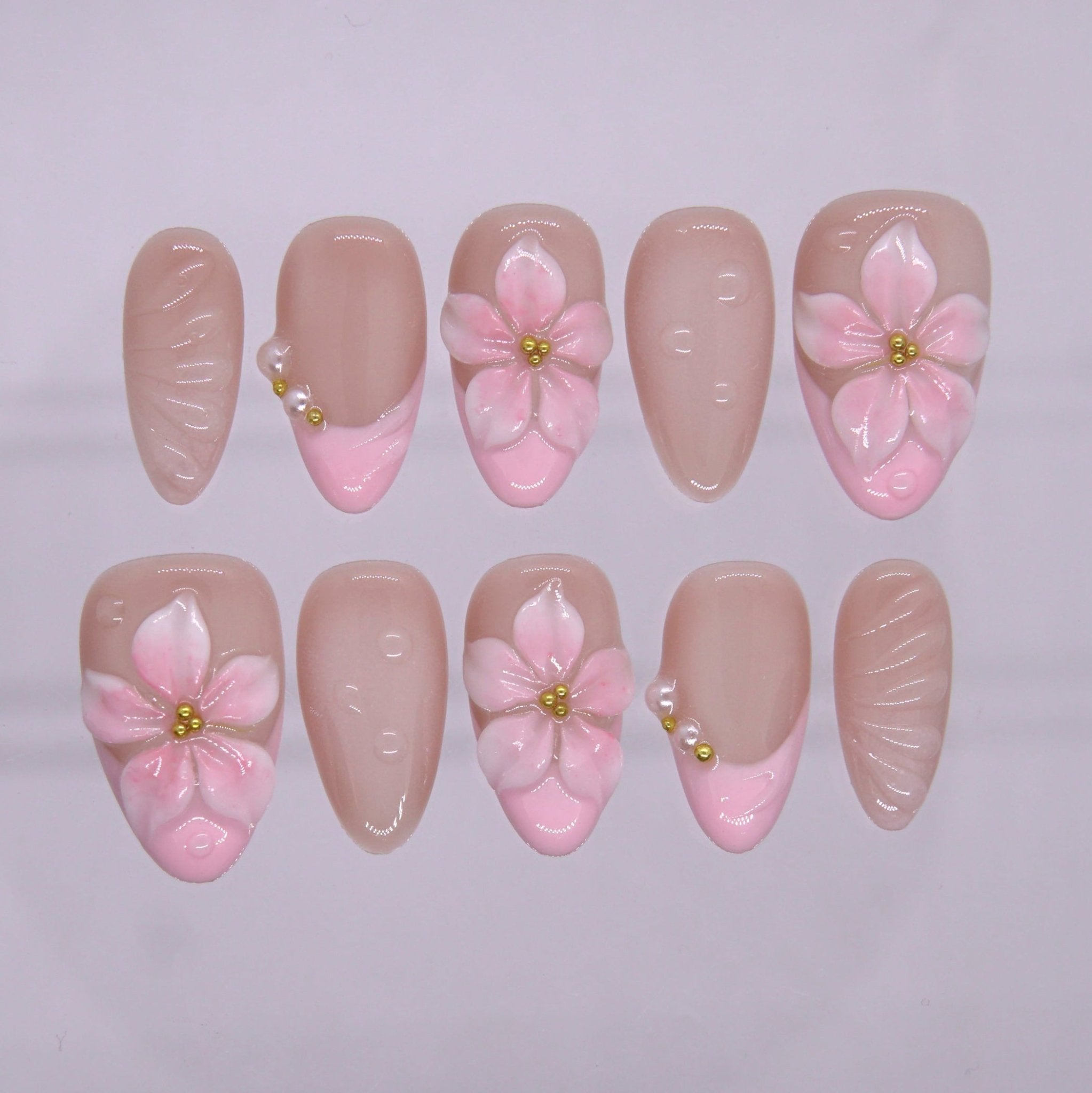 Pink 3D flower press on nails with blush French tip and gold bead center on nude base.