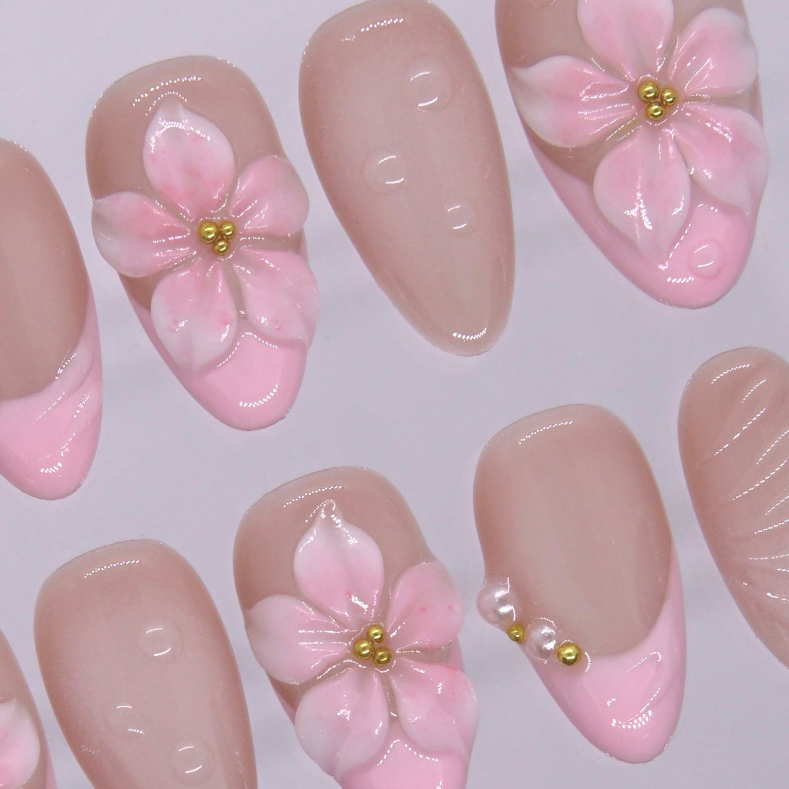 Side angle of blush French tip press on nails with pearl embellishment.