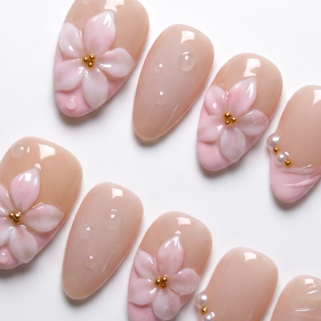 Side angle of blush French tip press on nails with pearl embellishment.