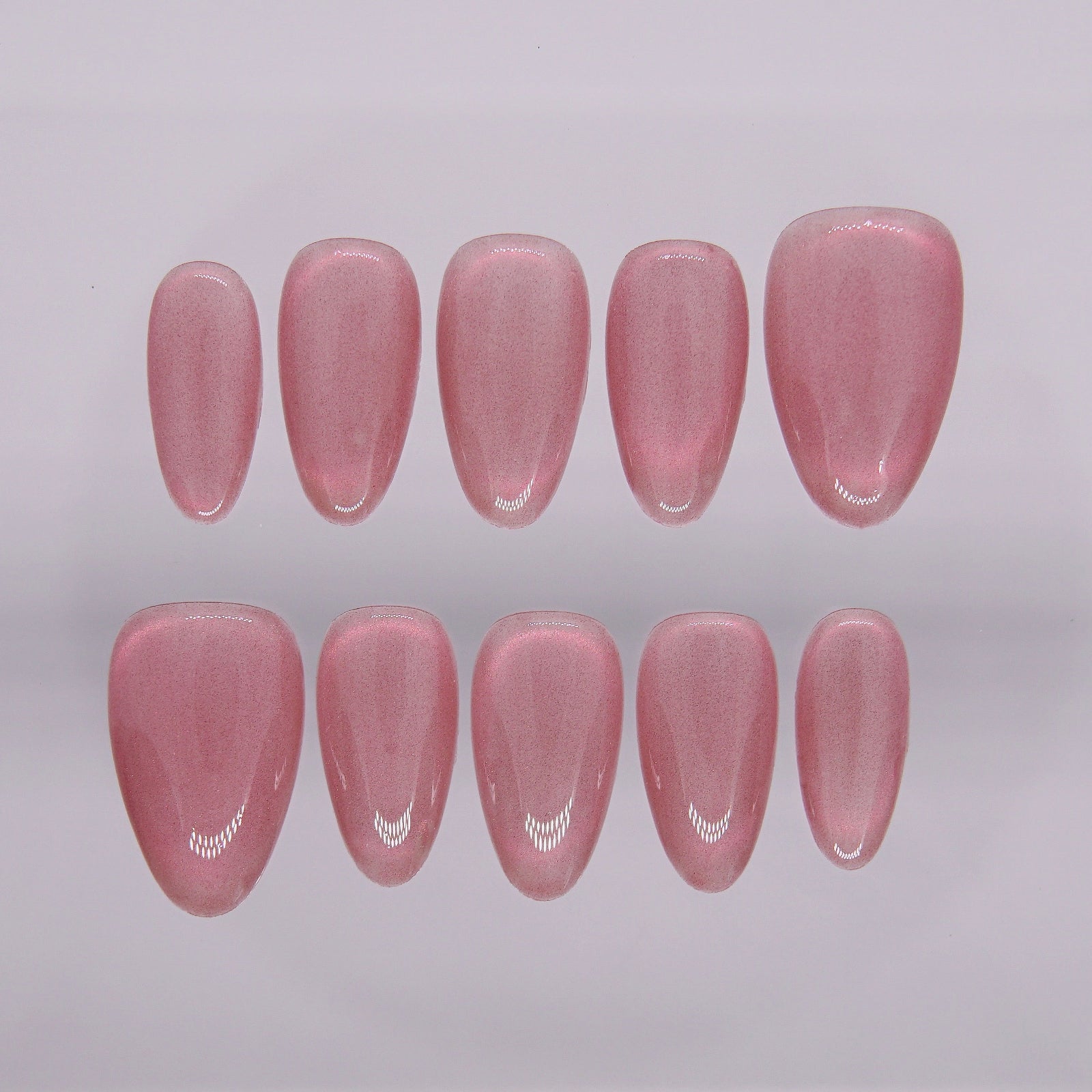 Close-up of Blush Rush press-on nails in coral red cat eye, glowing with fiery shimmer.