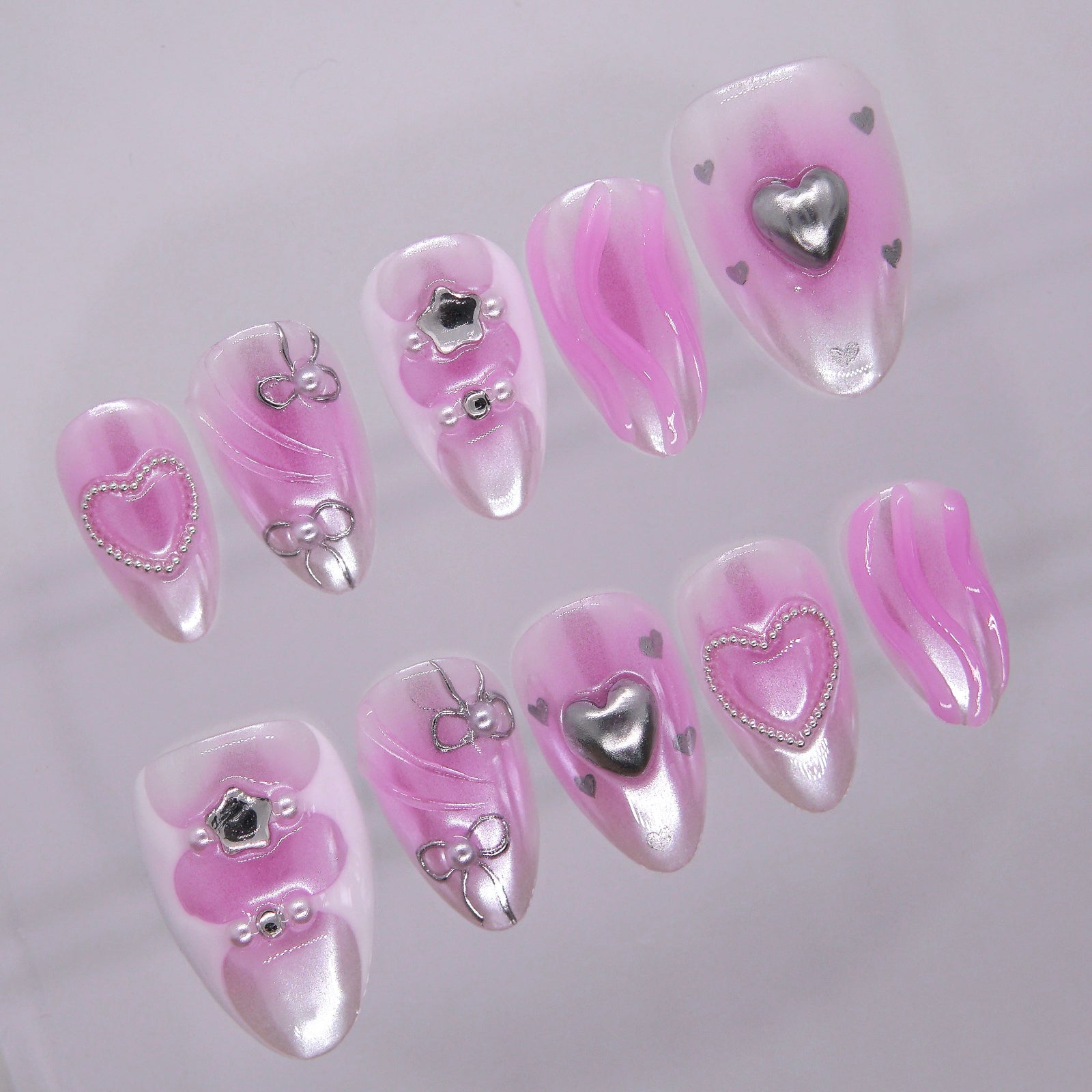 Side angle of handcrafted pink press-on nails featuring silver swirl and heart motifs