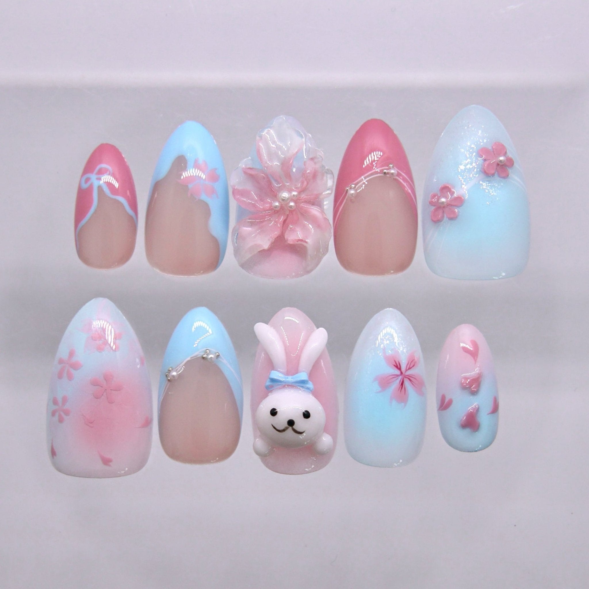 Fresh spring press on nails with pink and blue gradient, floral details, and a cute bunny design. Perfect for soft and romantic looks.