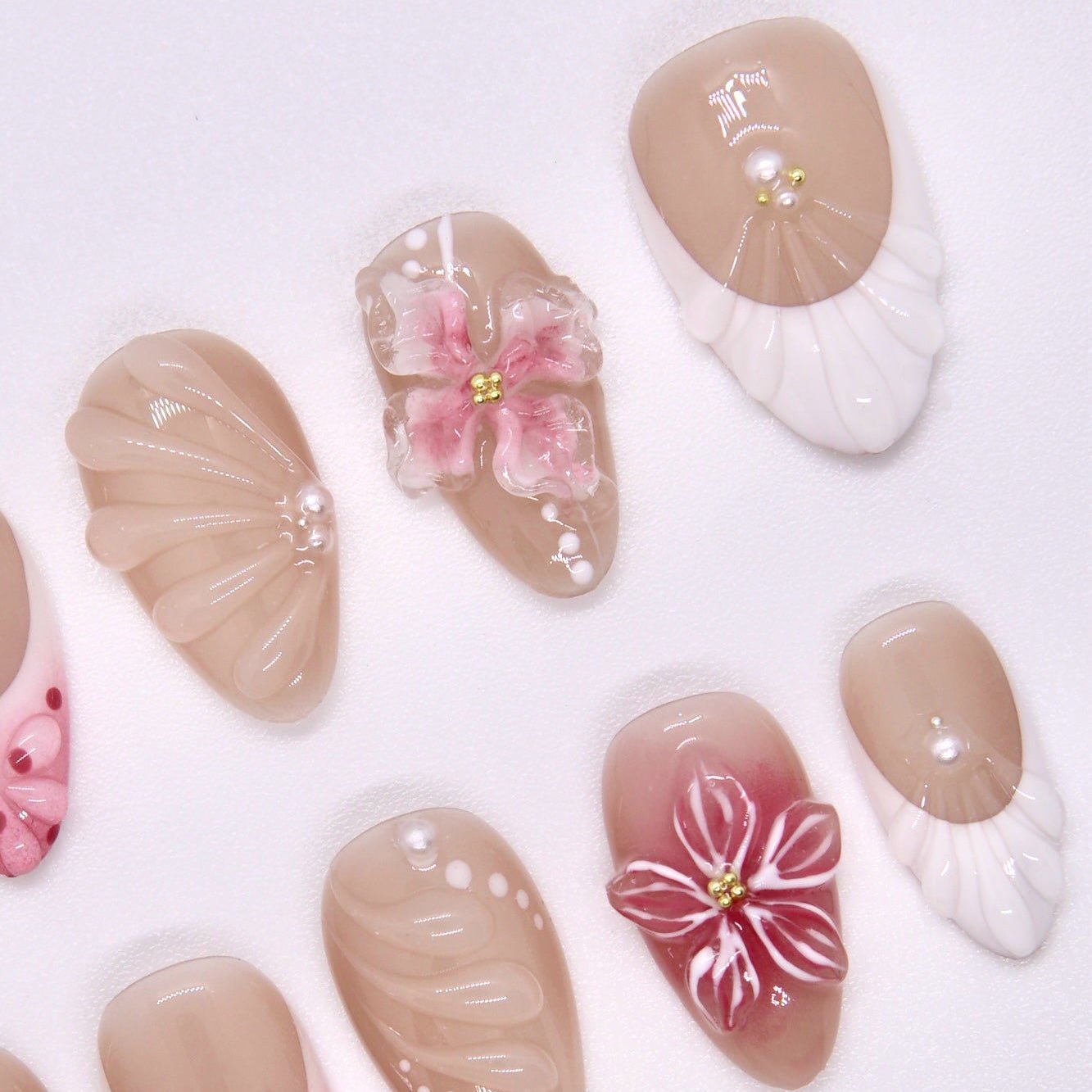 Close-up of sculpted floral and butterfly details on nude ombré press-on nails.