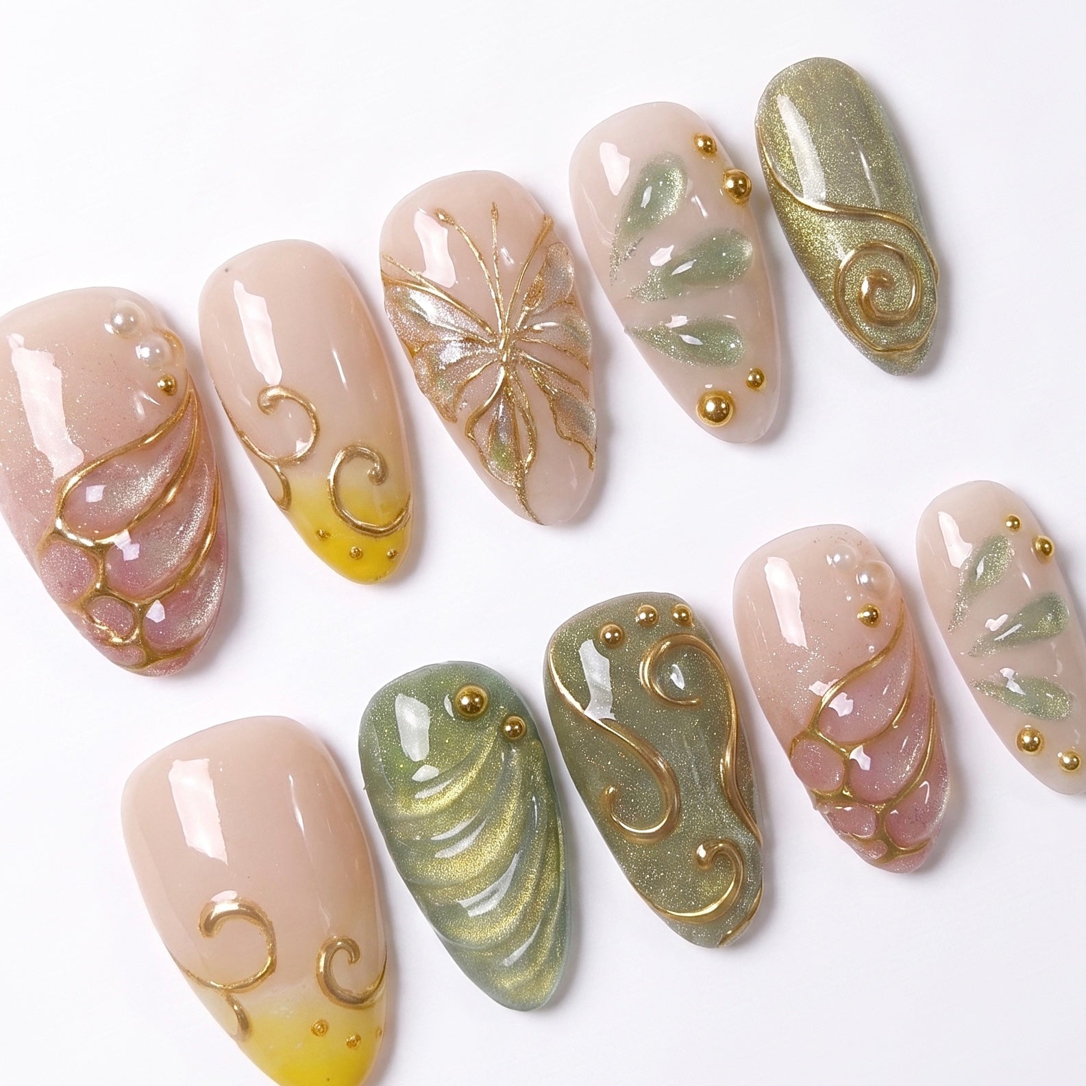 Close-up of Butterfly Grove press-on nails featuring butterfly wing nail art, soft sage green, blush pink, yellow tips, and dimensional gold details