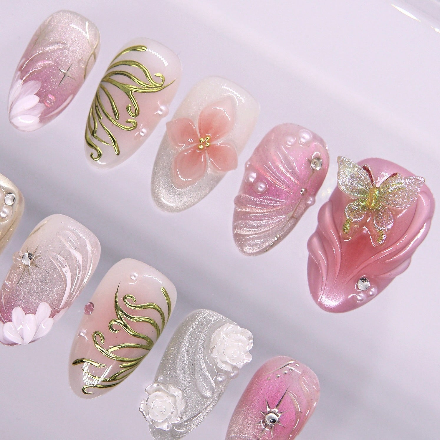 Close-up of butterfly and flower sculpted press-on nail with shimmer pink base.