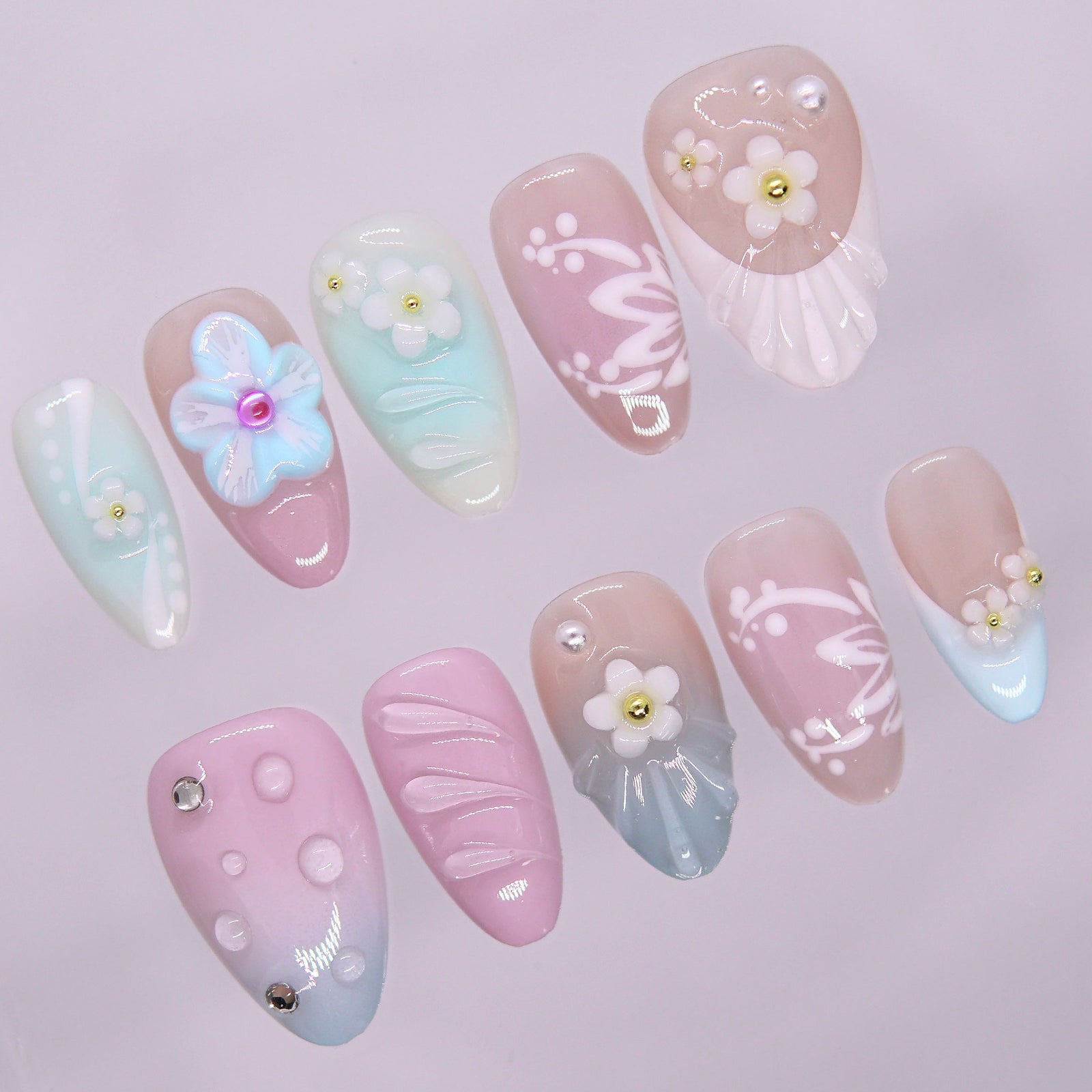Close-up of pearly flowers and shell details on pastel press-on nails with soft glossy finish.
