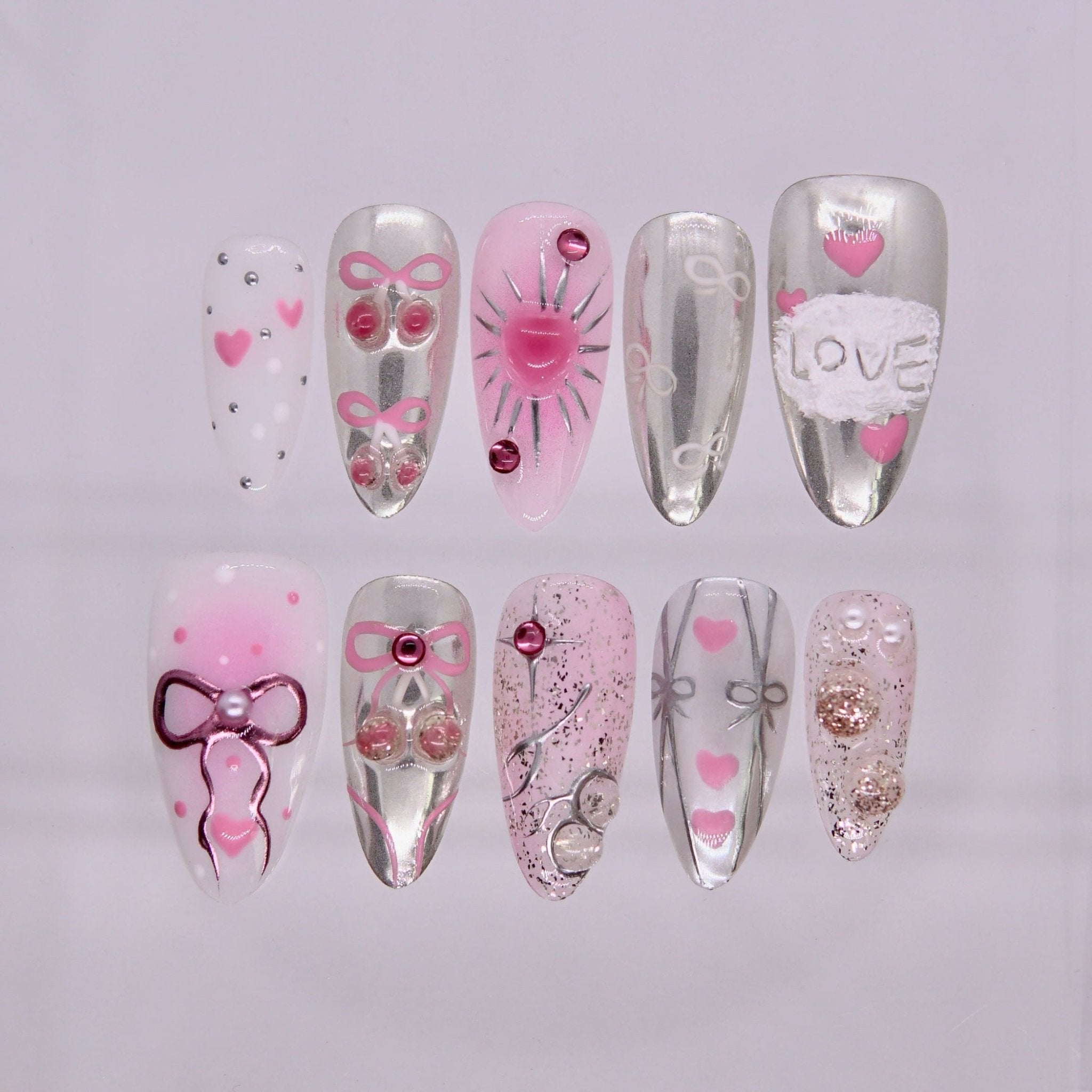 Rat zodiac press-on nails in silver chrome and blush pink with heart accents, bows, and soft sparkle details representing Cherish self love energy.
