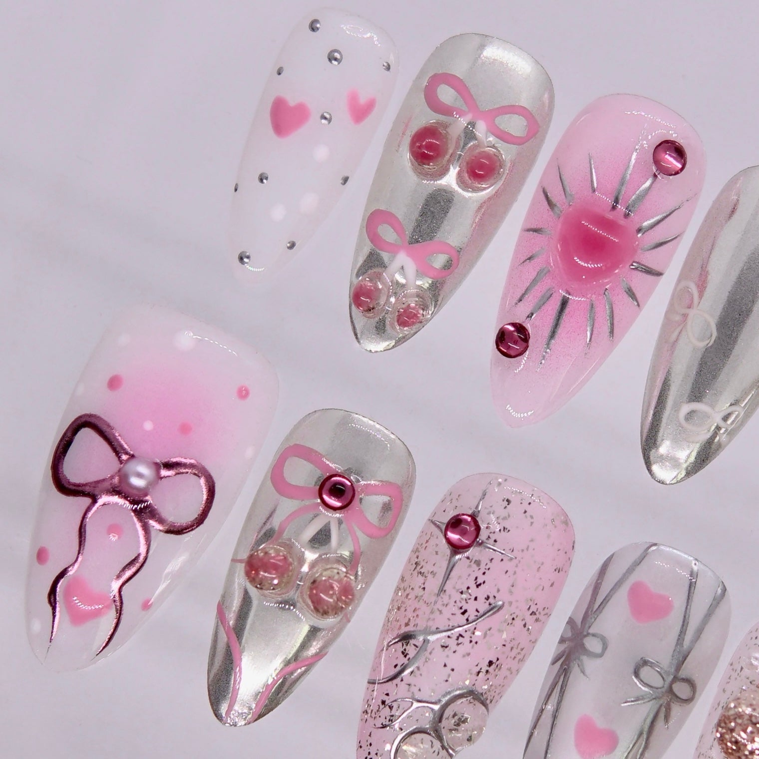 Detail view of Rat zodiac Valentine nails with bow accents, blush pink details, and reflective silver surface.
