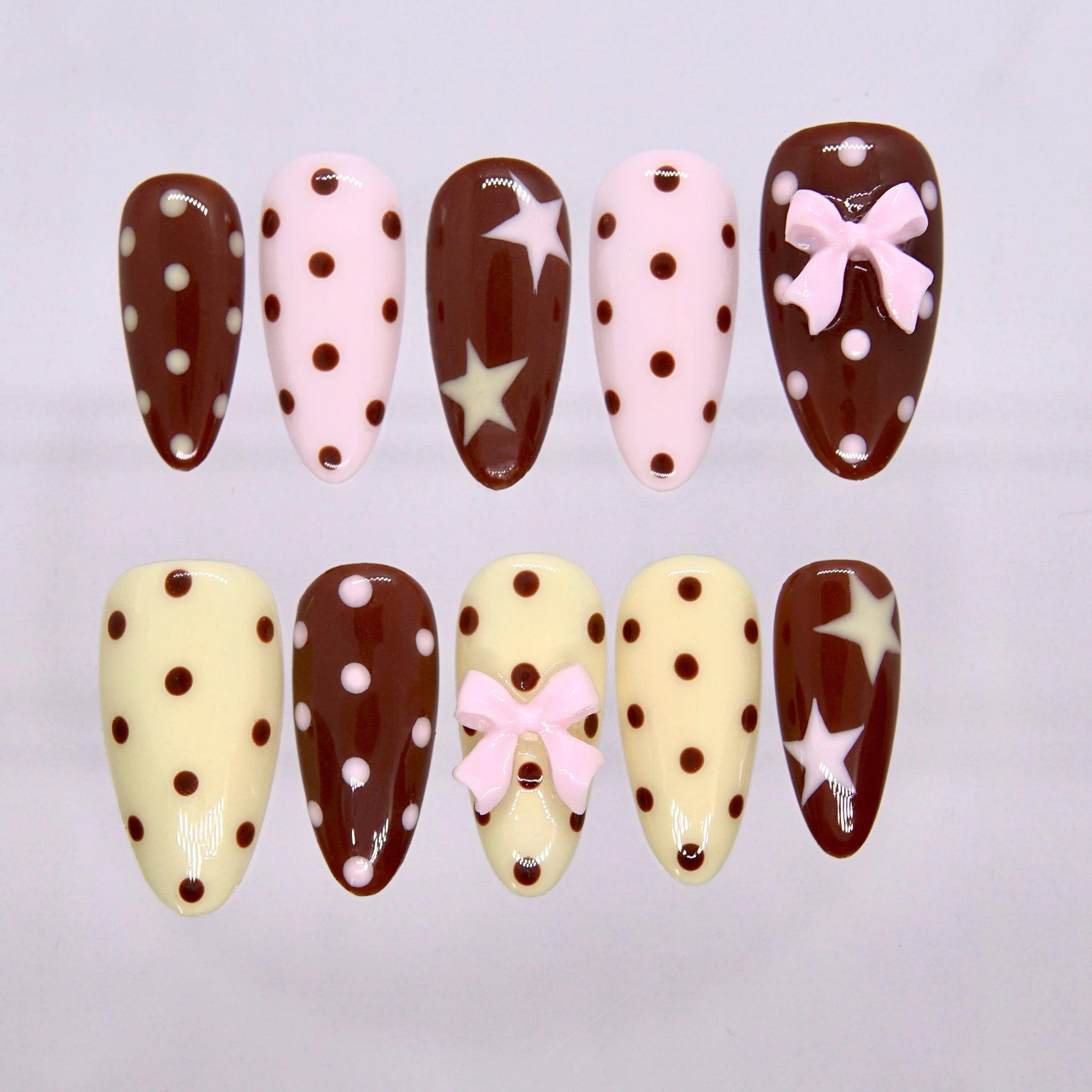 Choco Daisy press-on nails featuring chocolate brown, cream, and pink polka-dot design with 3D bow details.