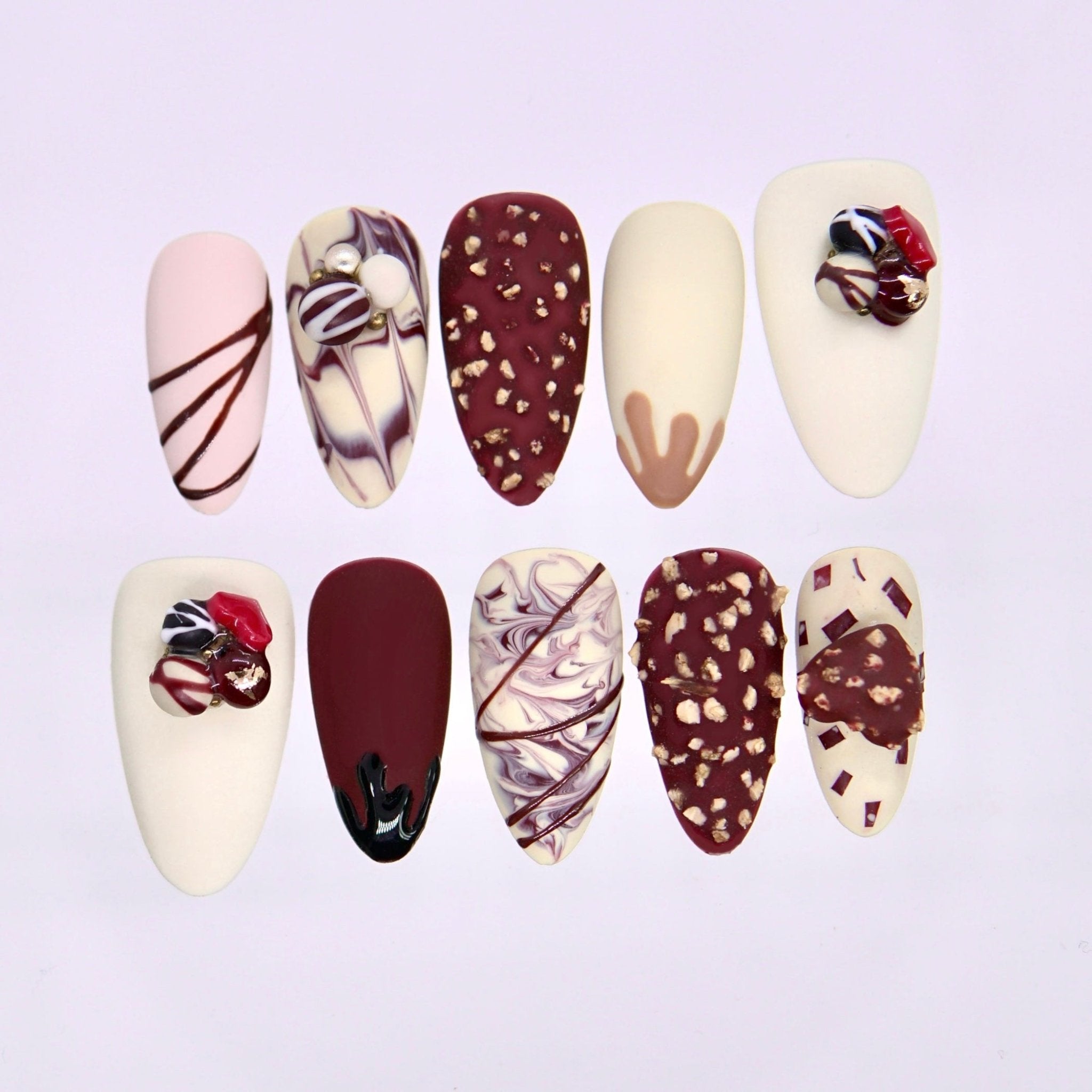 Handmade press on nails in cream and chocolate tones with marbled patterns and soft line details displayed on a clear stand
