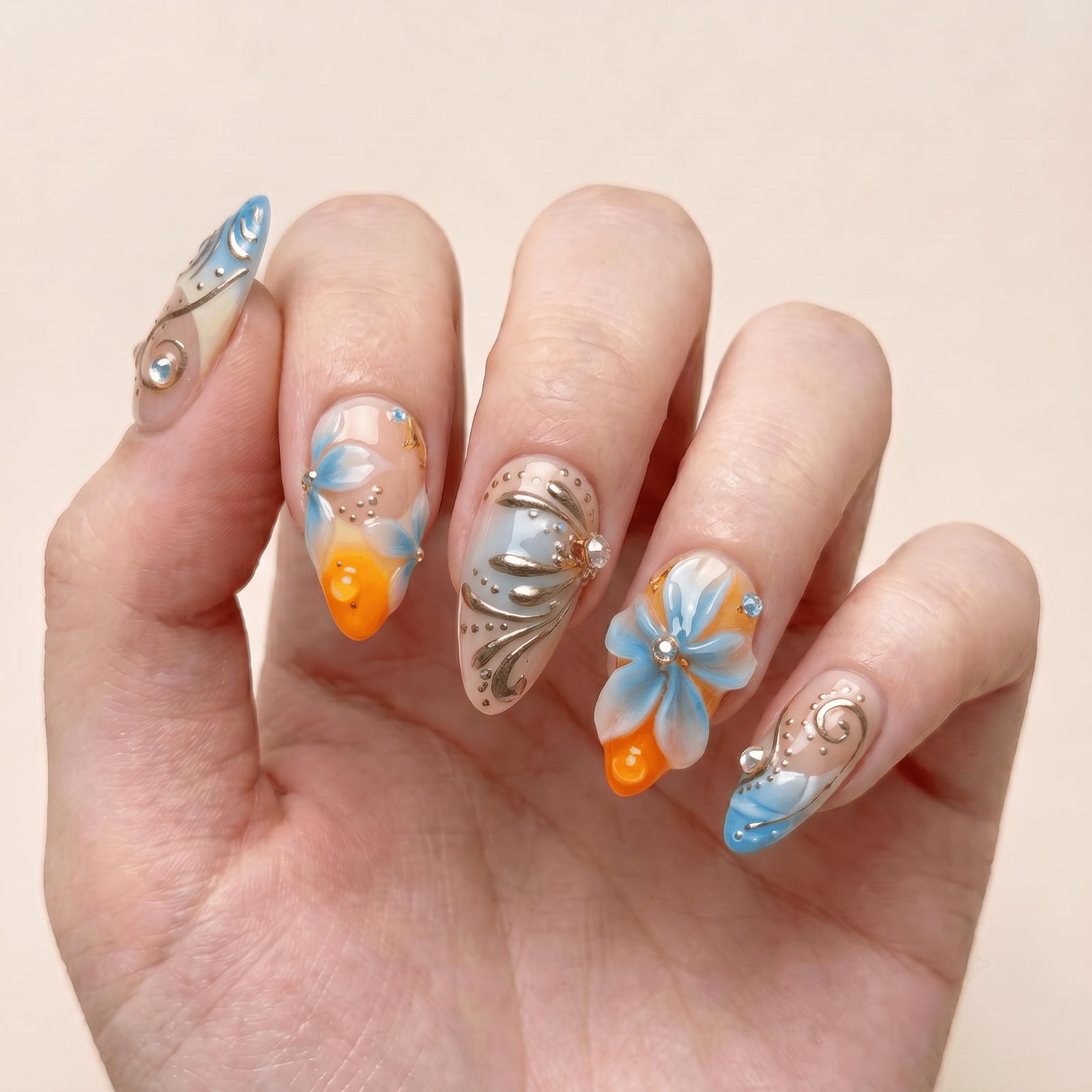 Blue and orange floral press-on nails worn on hands by Nailsium