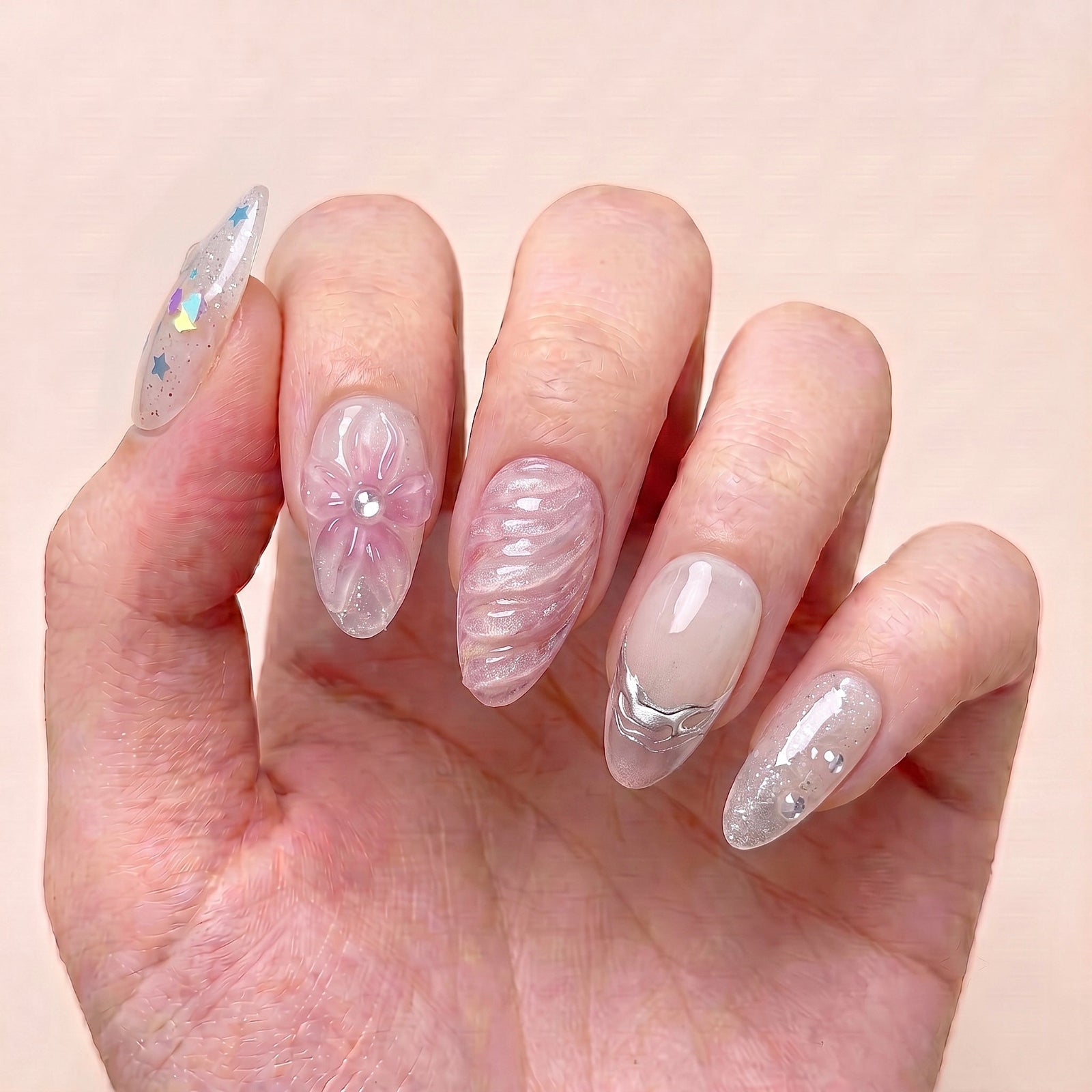 Dewdrop Serenade handmade press-on nails worn on hand with blush pink floral nail art, sheer nude bases, and delicate silver flowing details
