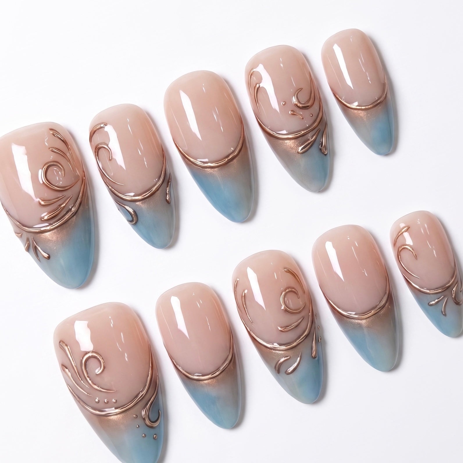 Close-up of Duskwater Script press-on nails featuring dusky blue French tips, sculpted copper-gold lines, and subtle shimmer